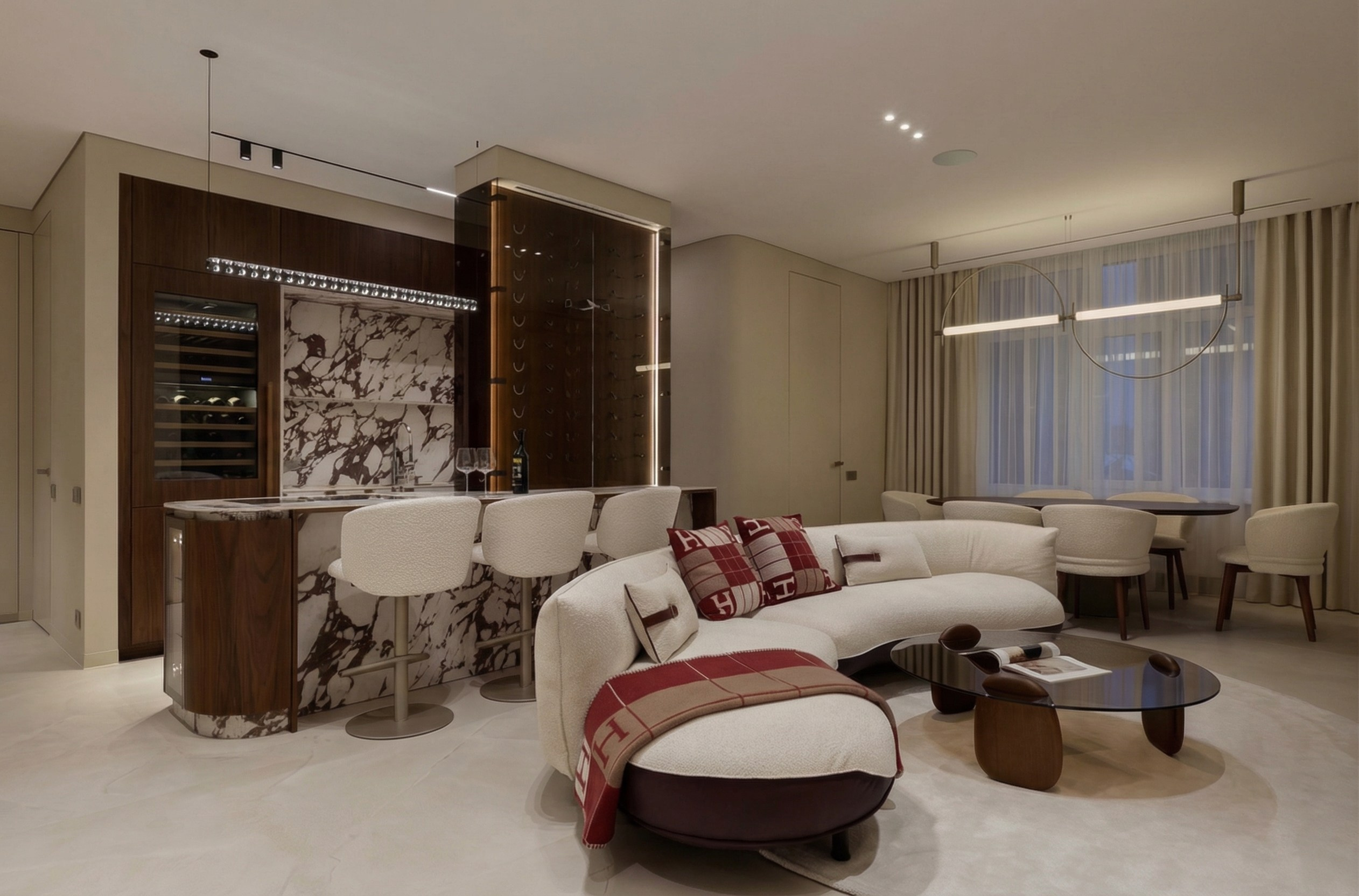 Интерьер кухни-гостиной в современном премиальном стиле от Валерии Котович: радиусный диван букле, винная витрина с подсветкой, обеденная группа и скрытые двери в потолок.