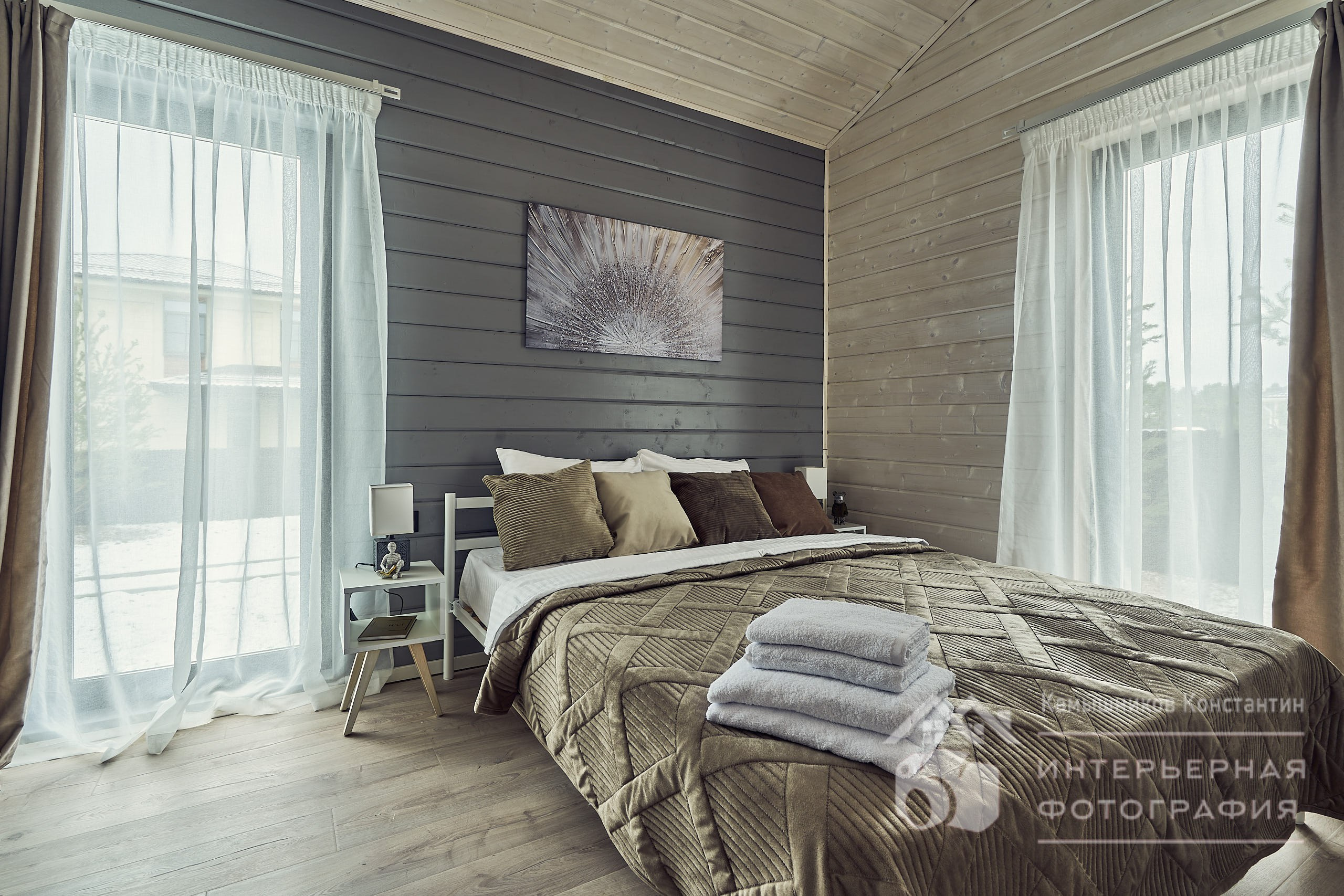 Интерьерная фотография кровати на фоне панорамных окон в спальне загородного дома в Московской области