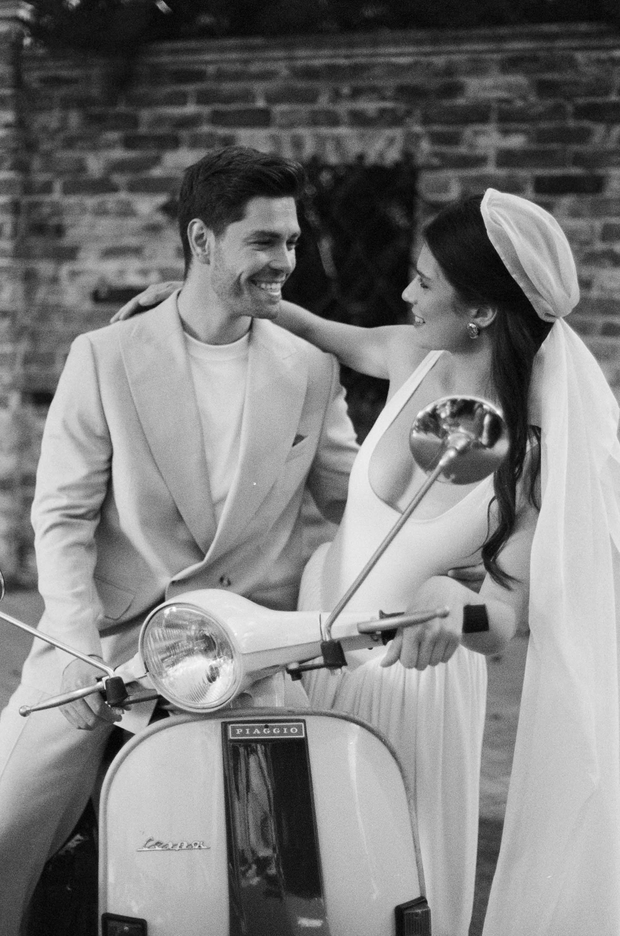 Чёрно-белый плёночный кадр: жених и невеста на винтажной Vespa