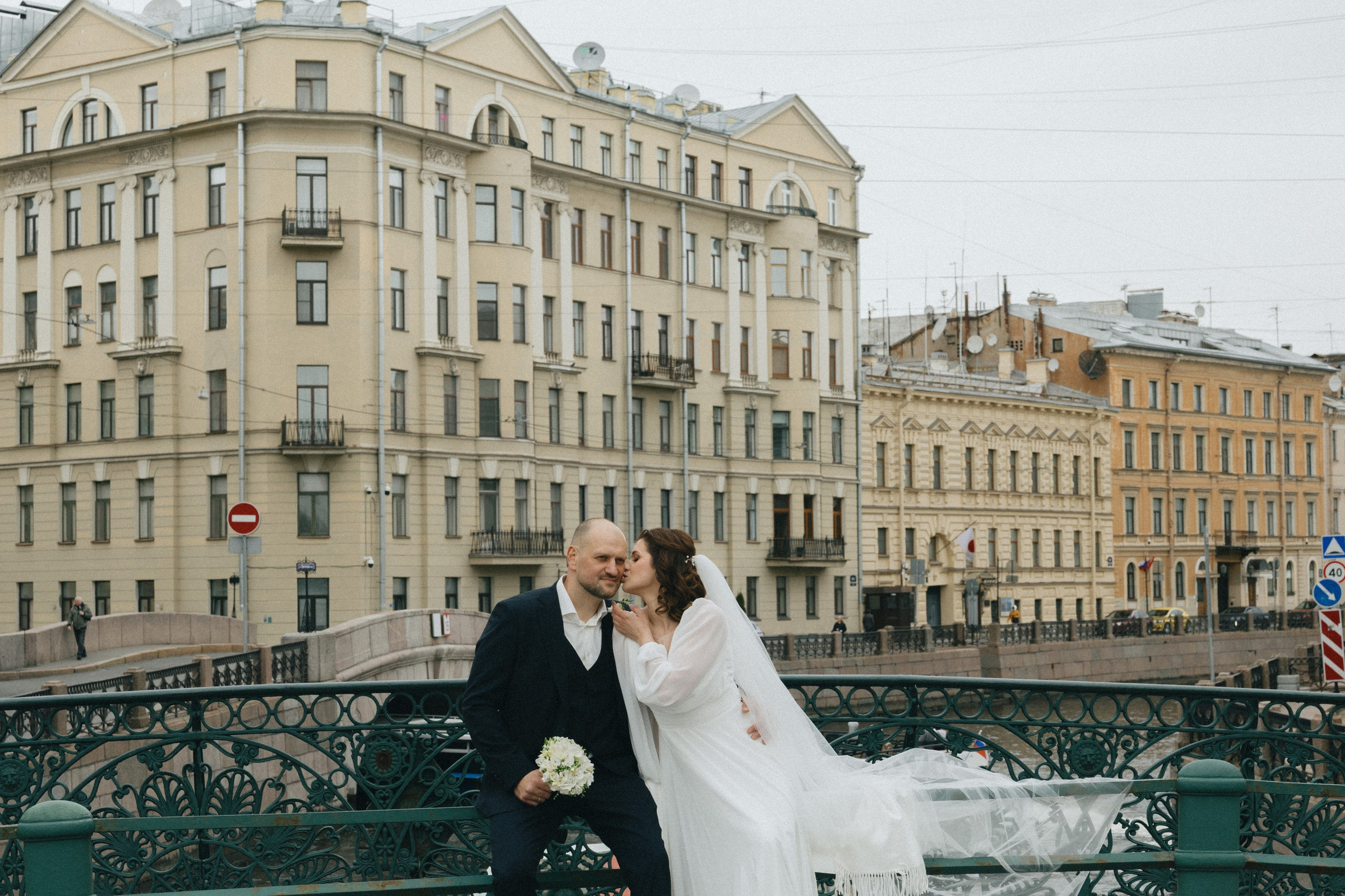 Свадебная прогулка вдоль каналов Петербурга, жених и невеста на фоне набережной.
