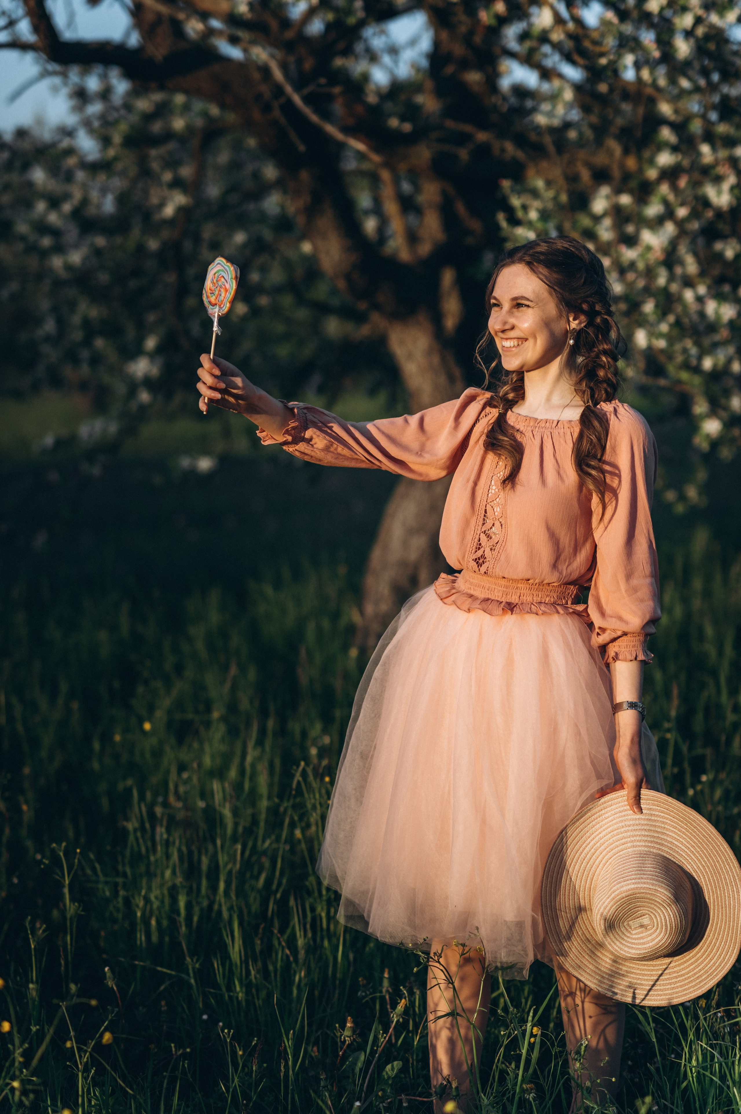 Девушка улыбается во время заката в яблоневом саду