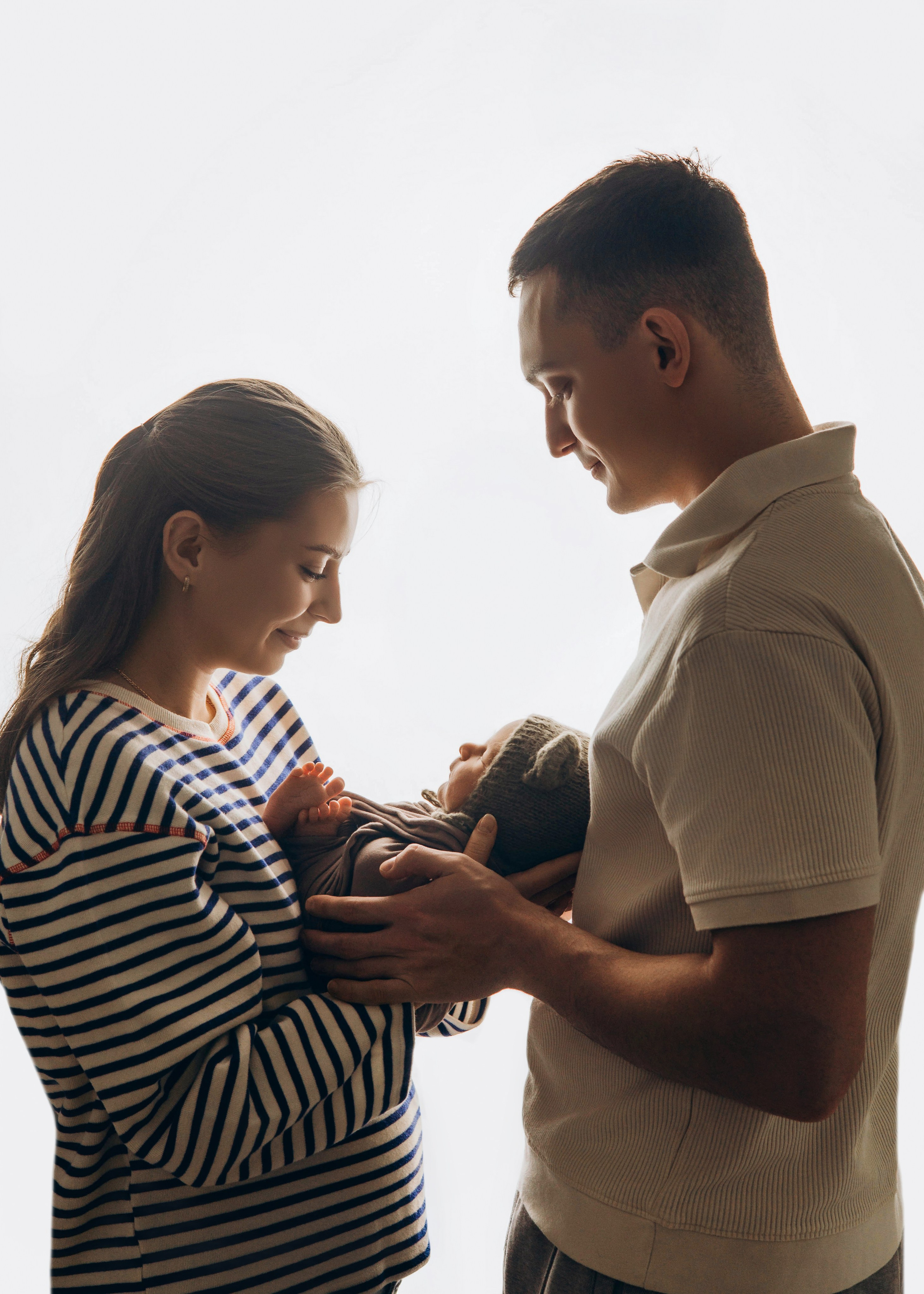 Родители держат новорождённого у окна, естественный свет и домашняя атмосфера — Видное