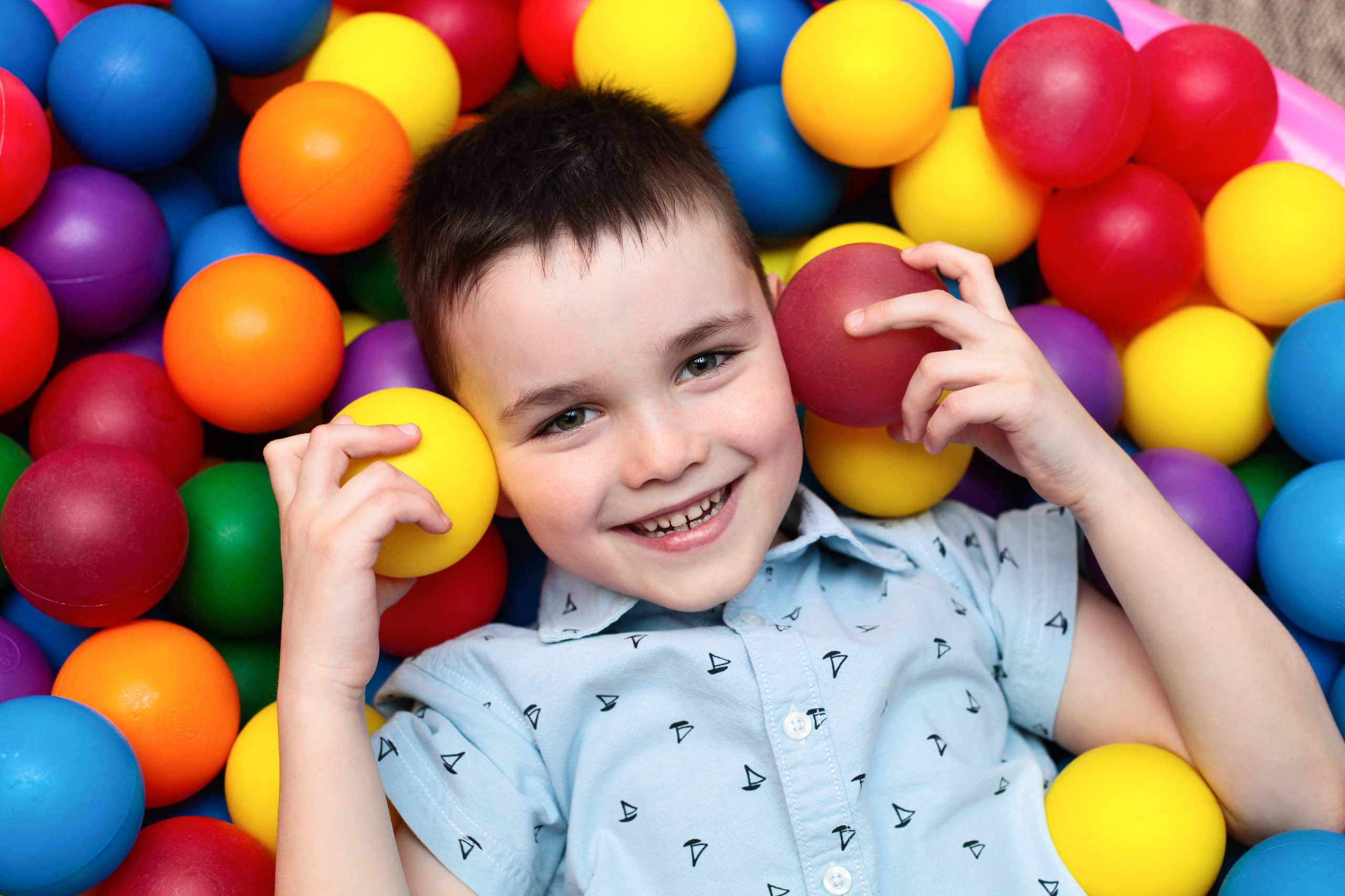 Мальчик лежит в шариках во время фотосессии для альбома выпускного