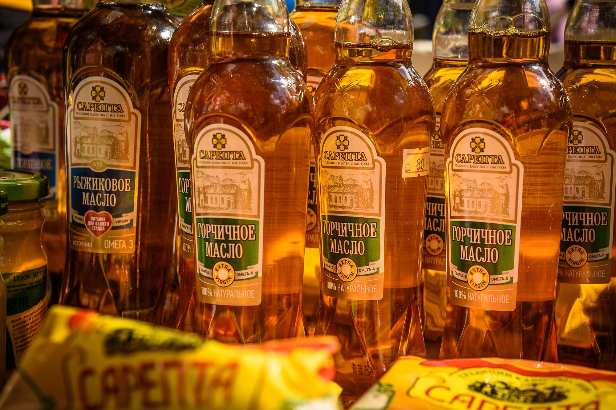 Бутылки горчичного и рыжикового масла на столе