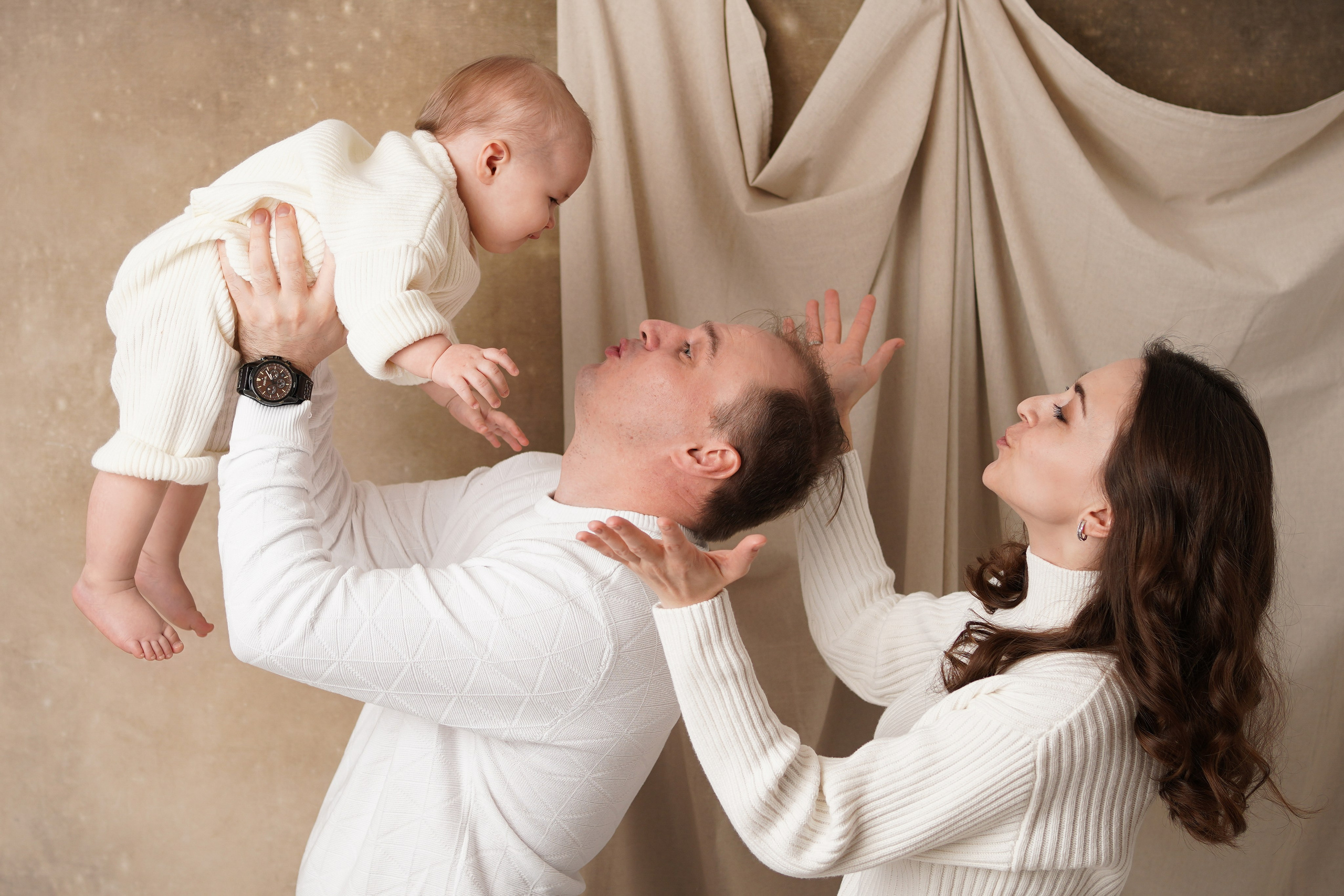 На семейных кадрах папа подбрасывает малышку вверх, она смеется.