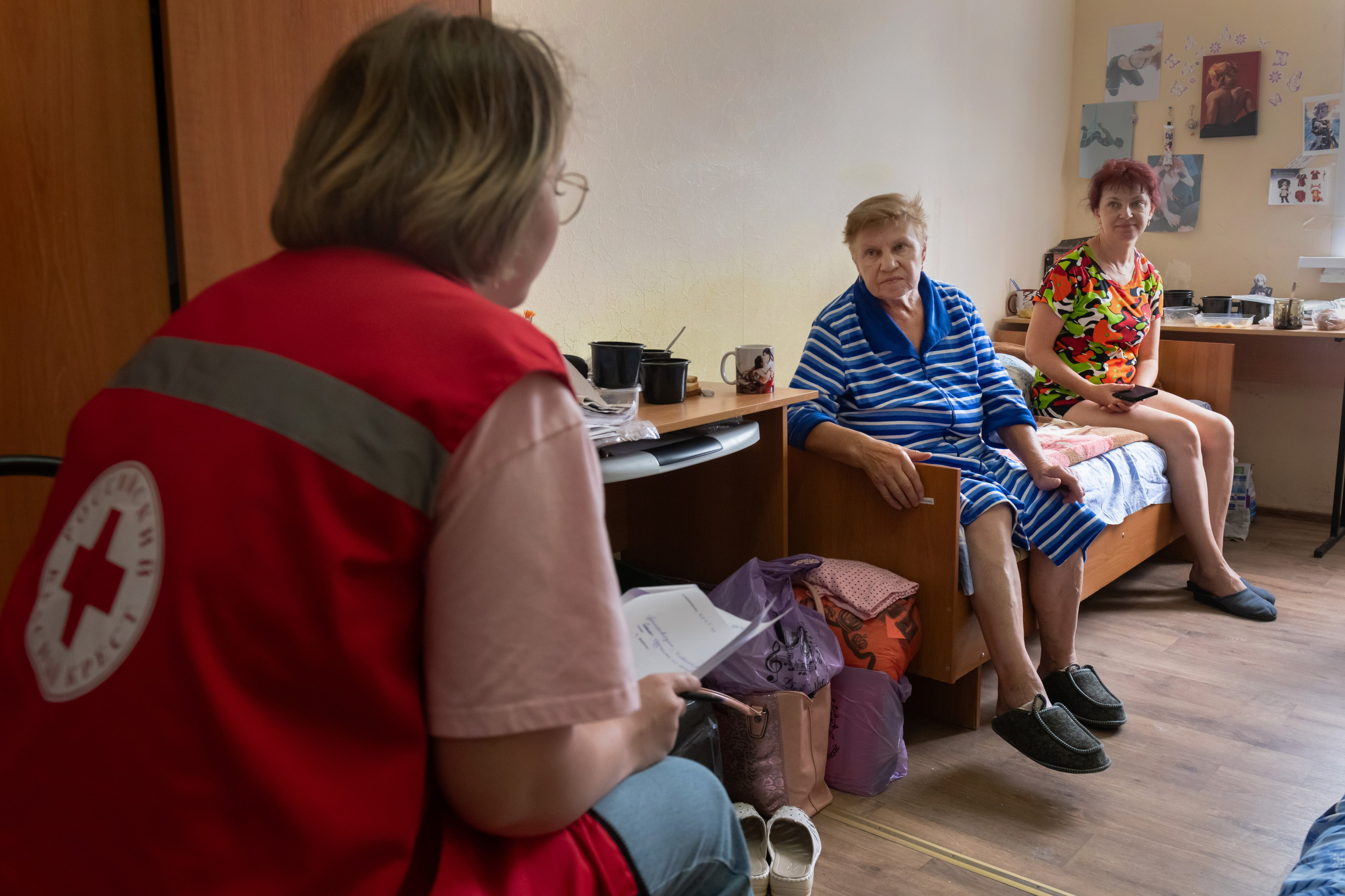 A Russian Red Cross worker, back to a camera, listens to people evacuated from a fighting between Russian and Ukrainian forces in Kursk region, at a temporary residence center in Kursk, Russia, Sunday, Aug. 11, 2024. (AP Photo)