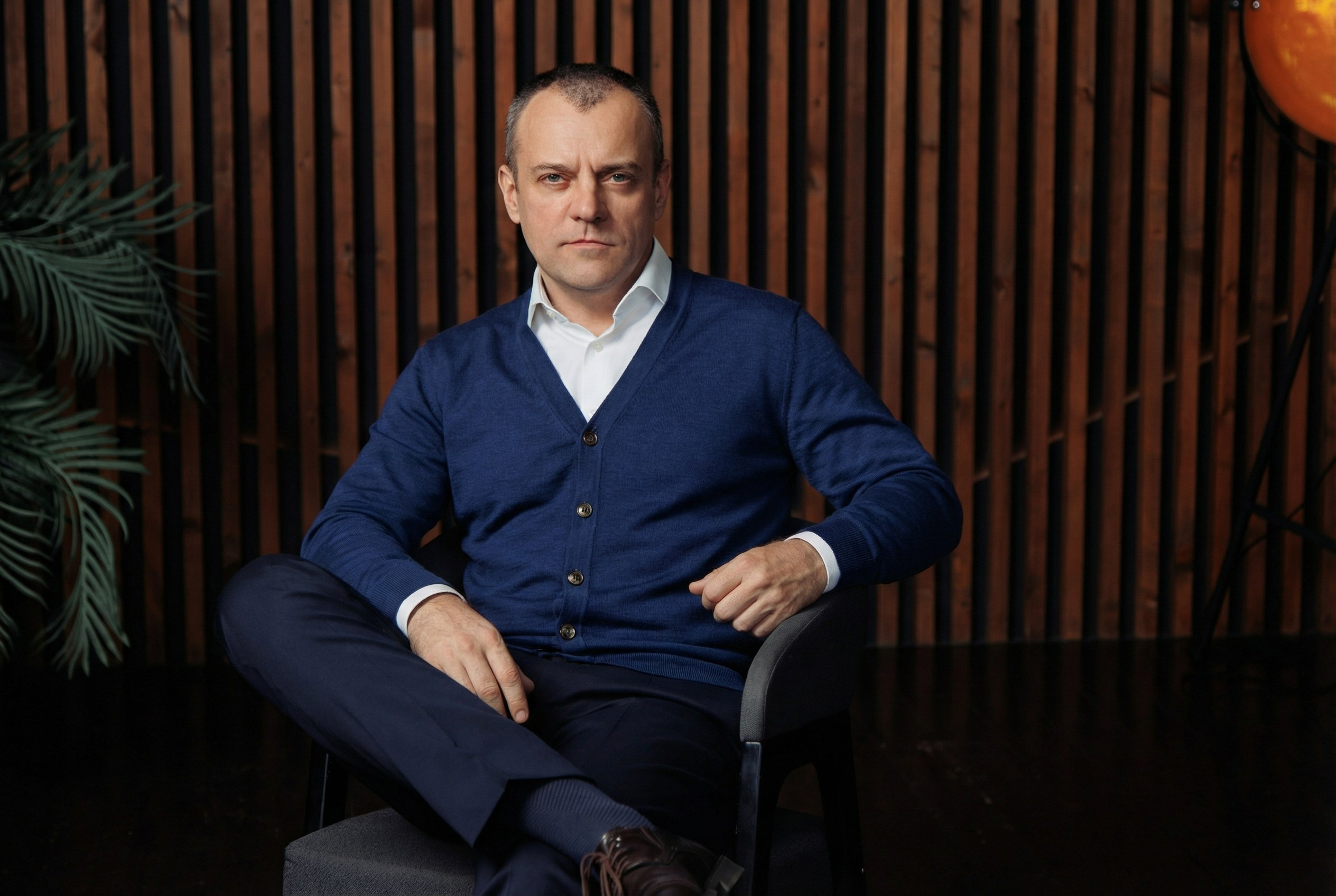 Мужчина в смарт кэжуал одежде сидит на стуле в интерьере офиса