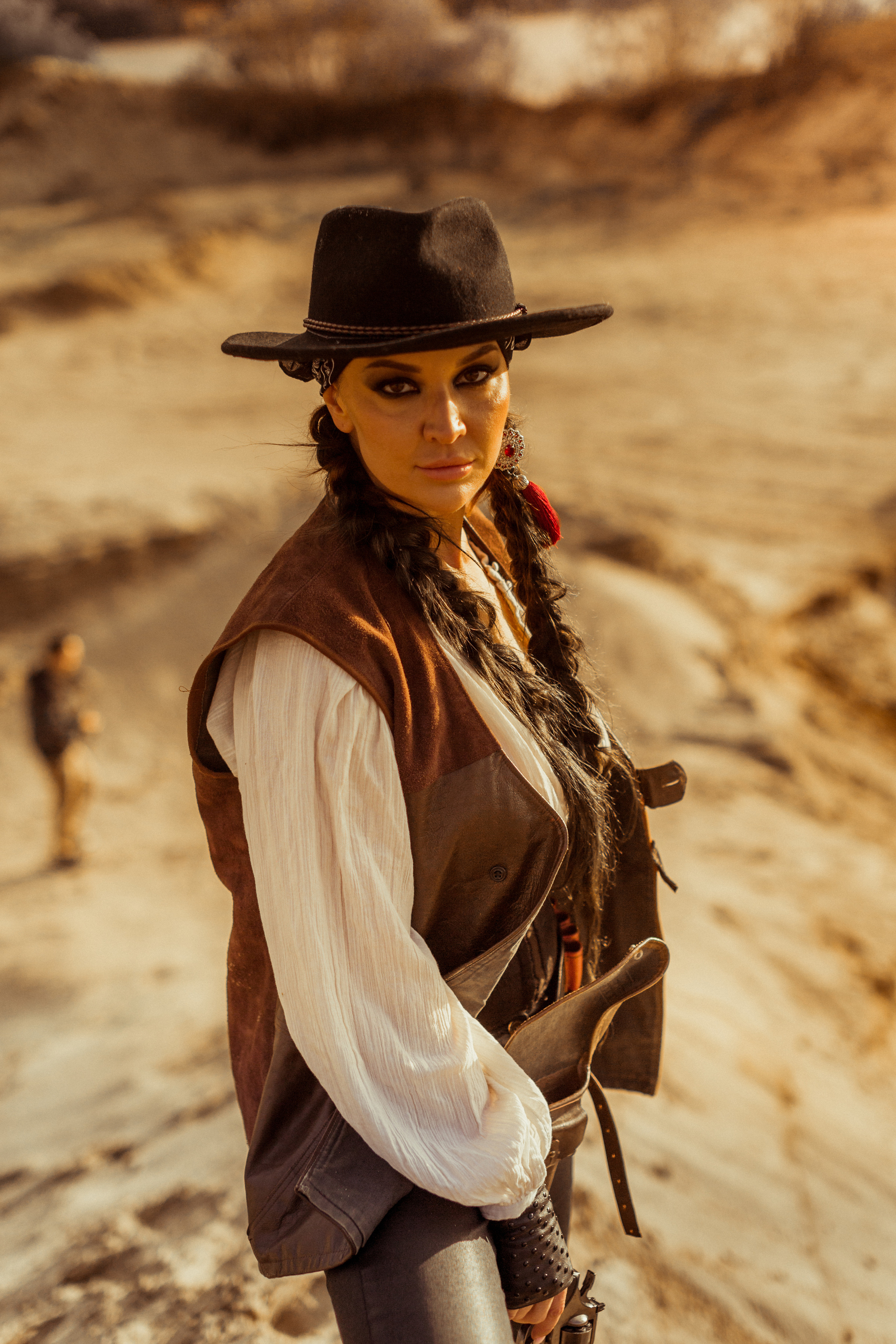 Девушка ковбой с револьвером вестерн на на бархане в пустыне.