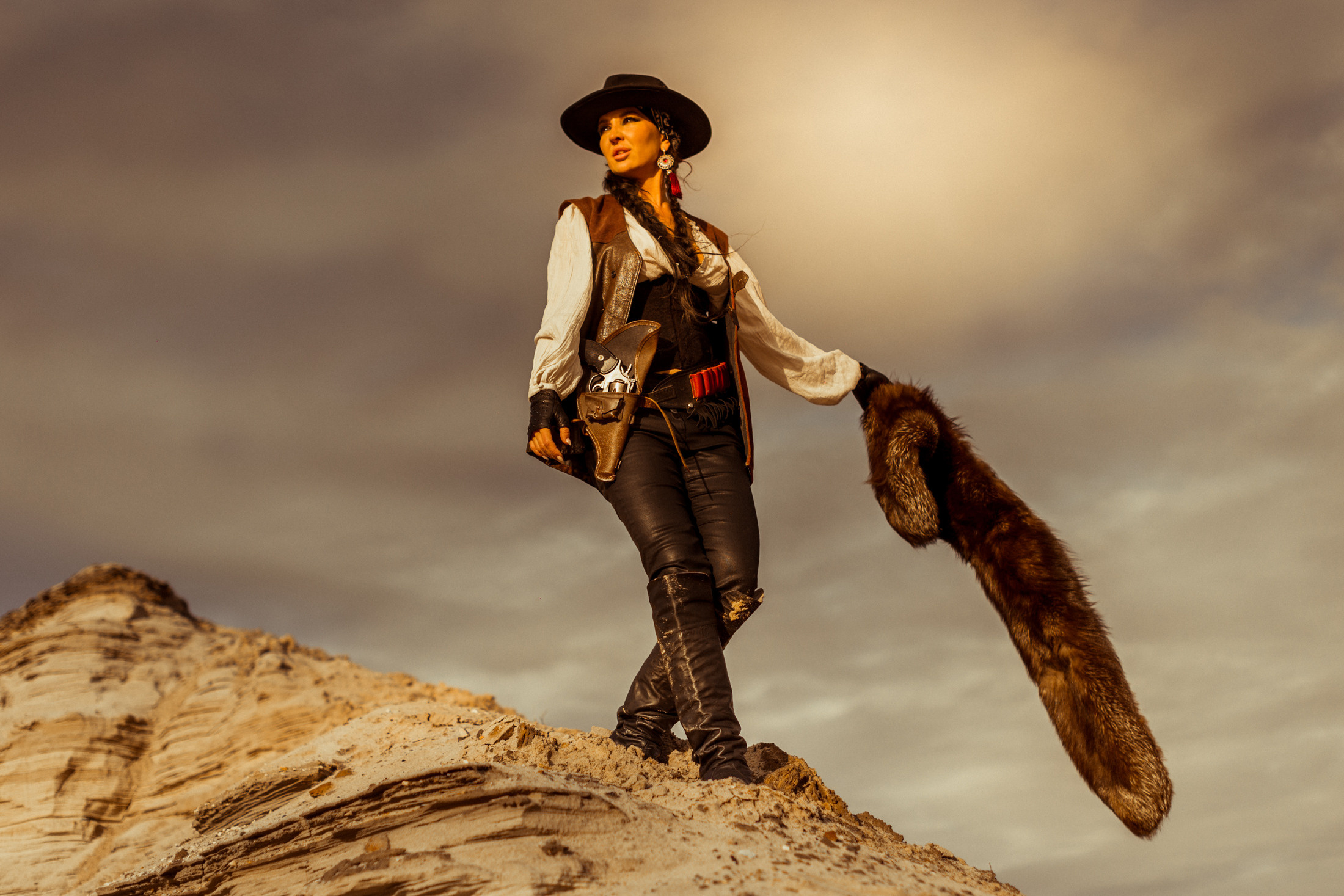 Девушка ковбой с револьвером вестерн на на бархане в пустыне.