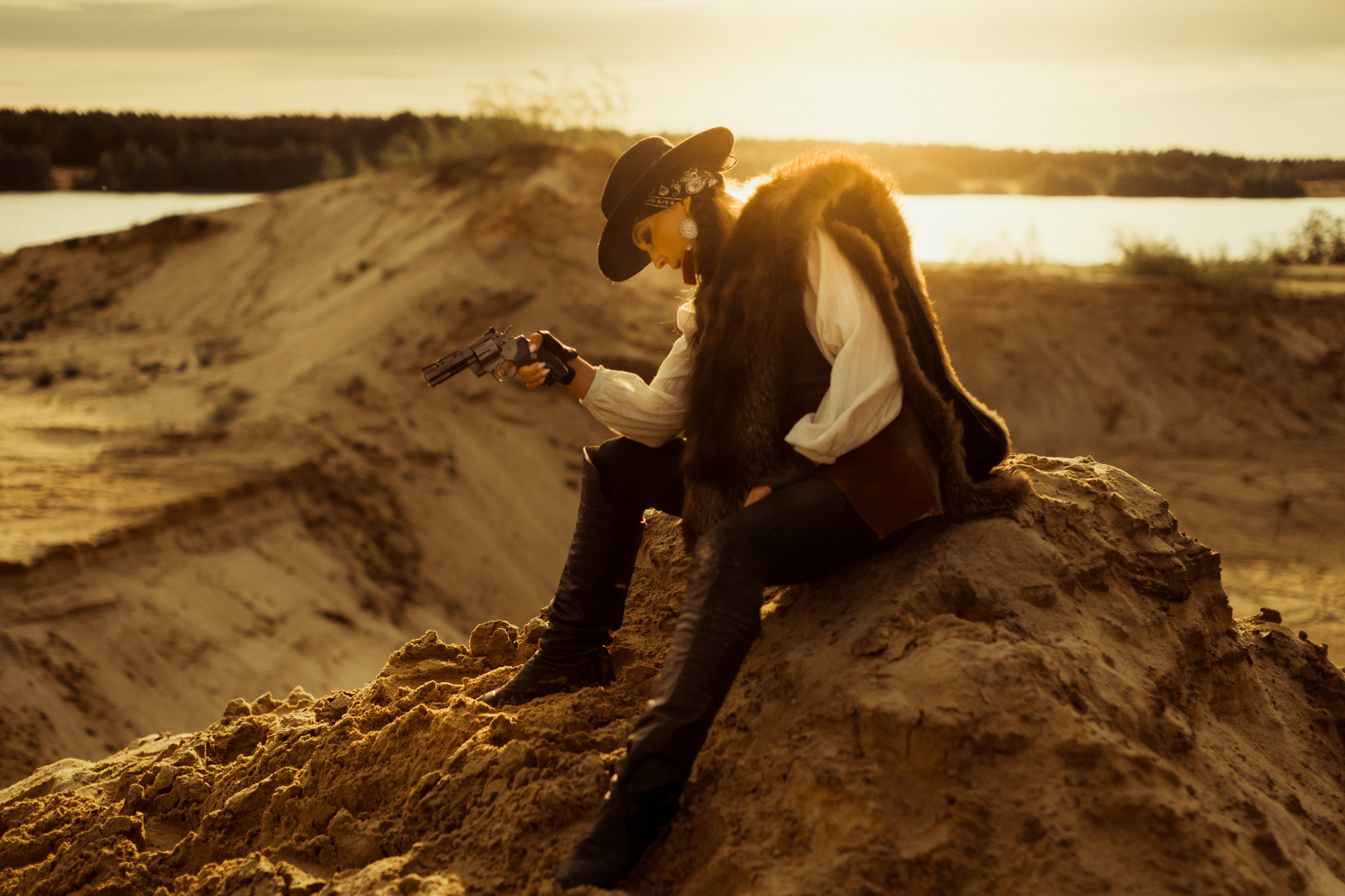Девушка ковбой с револьвером вестерн на на бархане в пустыне.