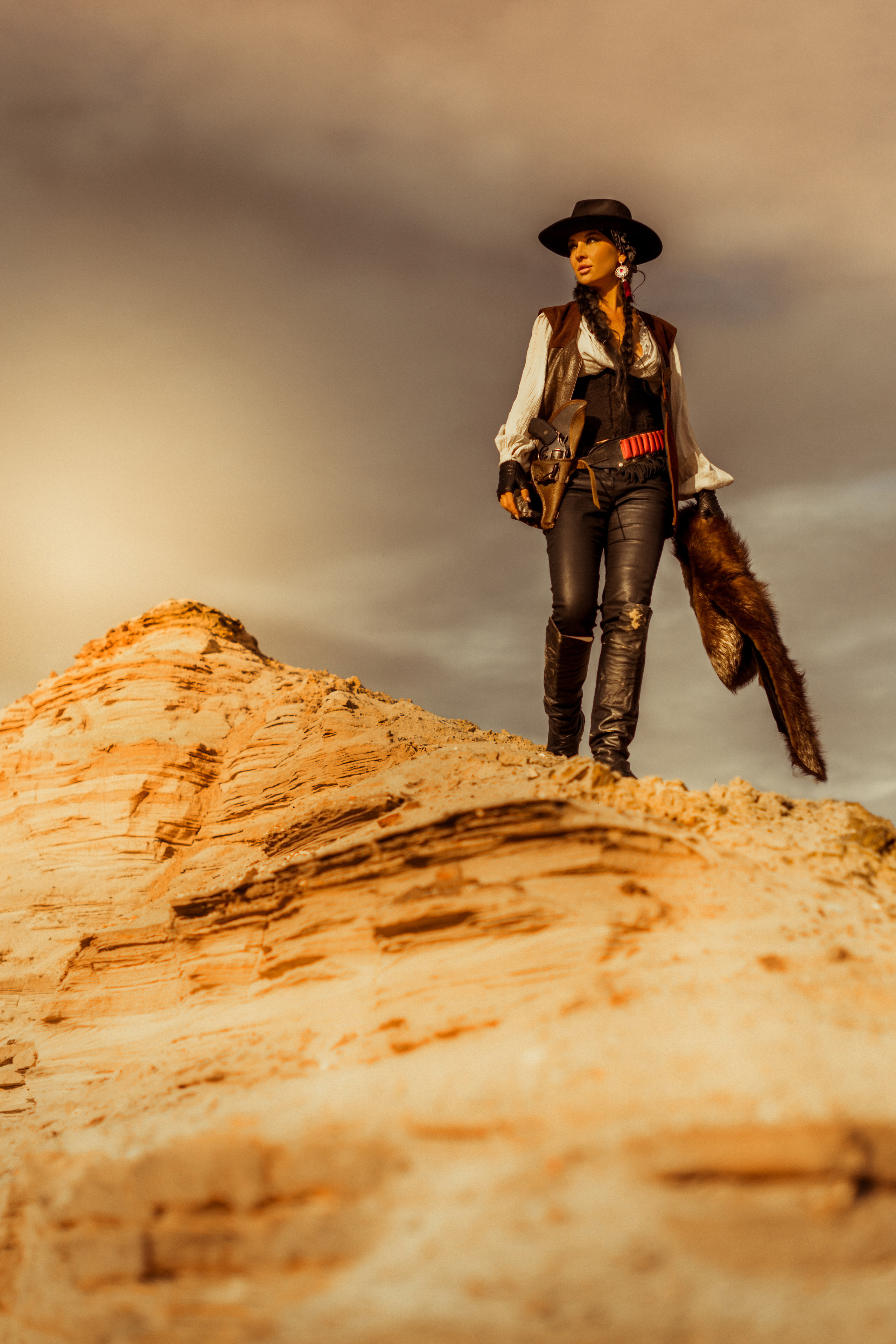 Девушка ковбой с револьвером вестерн на на бархане в пустыне.