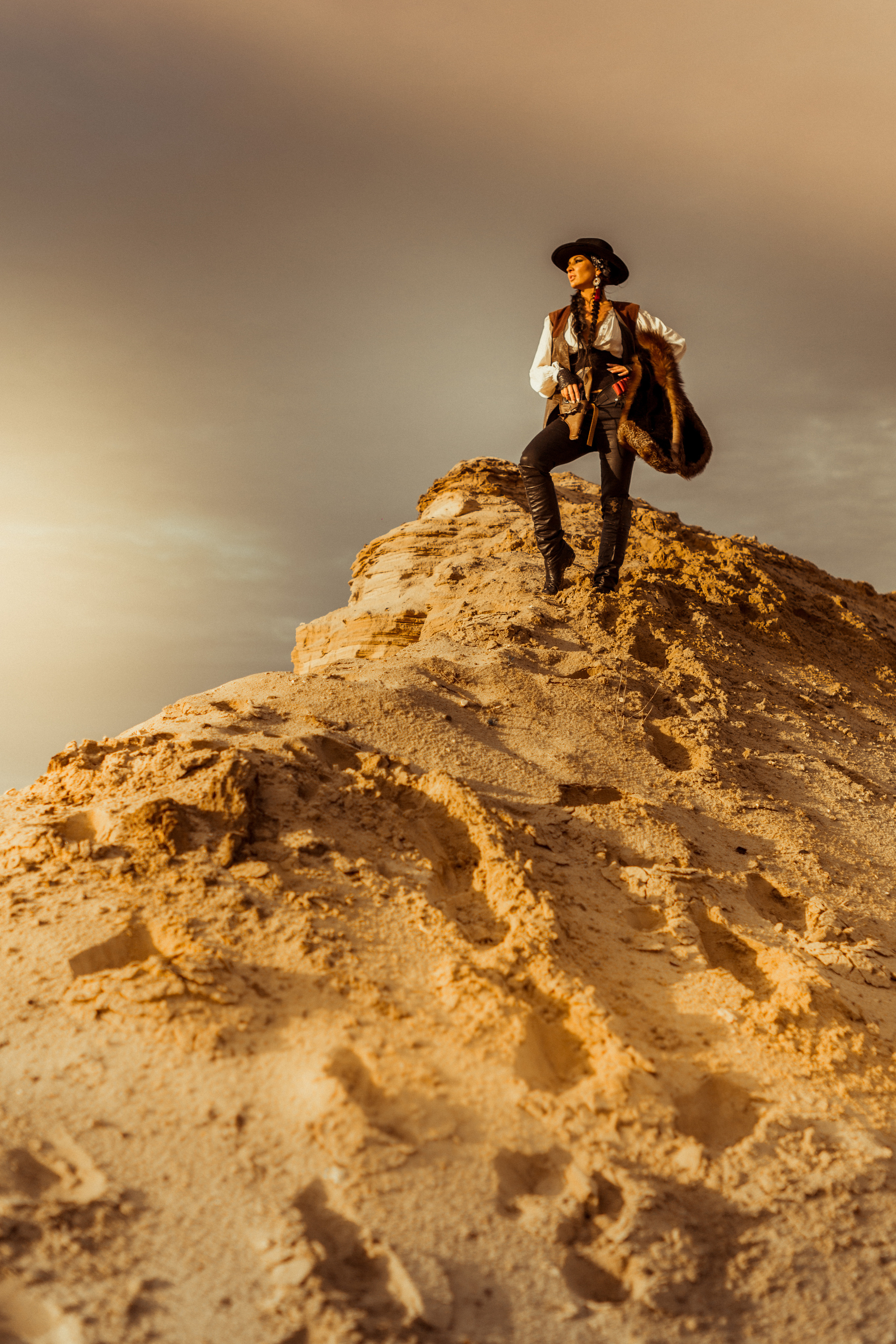 Девушка ковбой с револьвером вестерн на на бархане в пустыне.