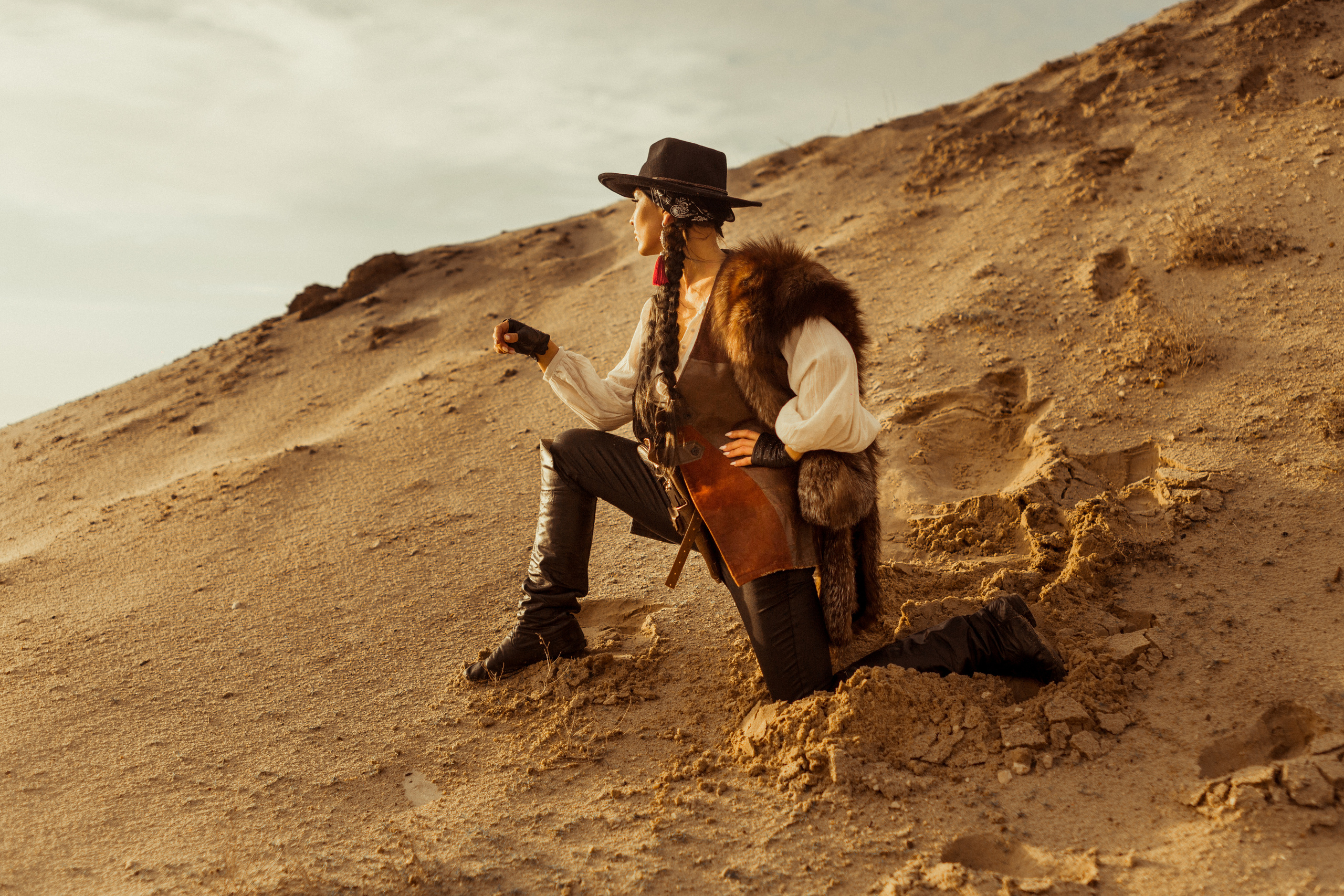 Девушка ковбой с револьвером вестерн на на бархане в пустыне.