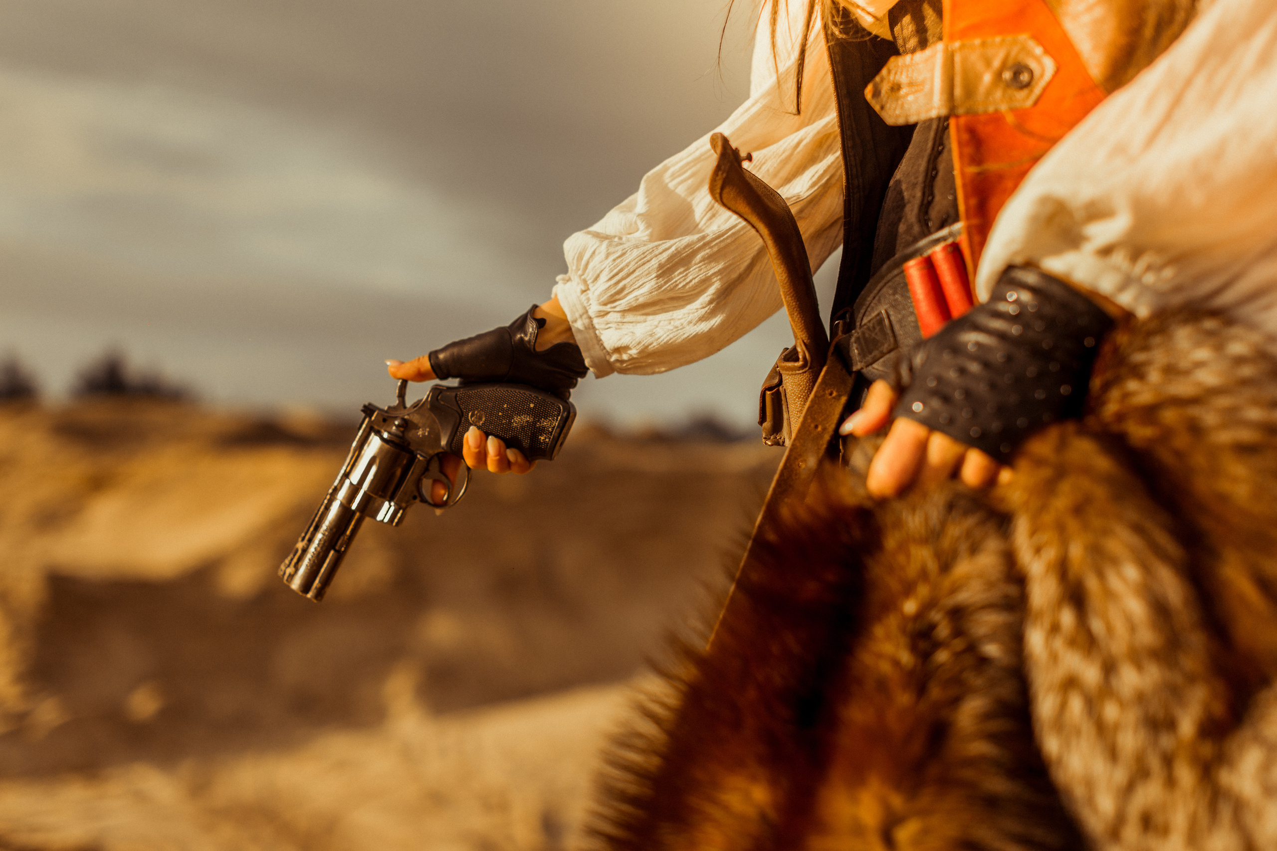 Девушка ковбой с револьвером вестерн на на бархане в пустыне.