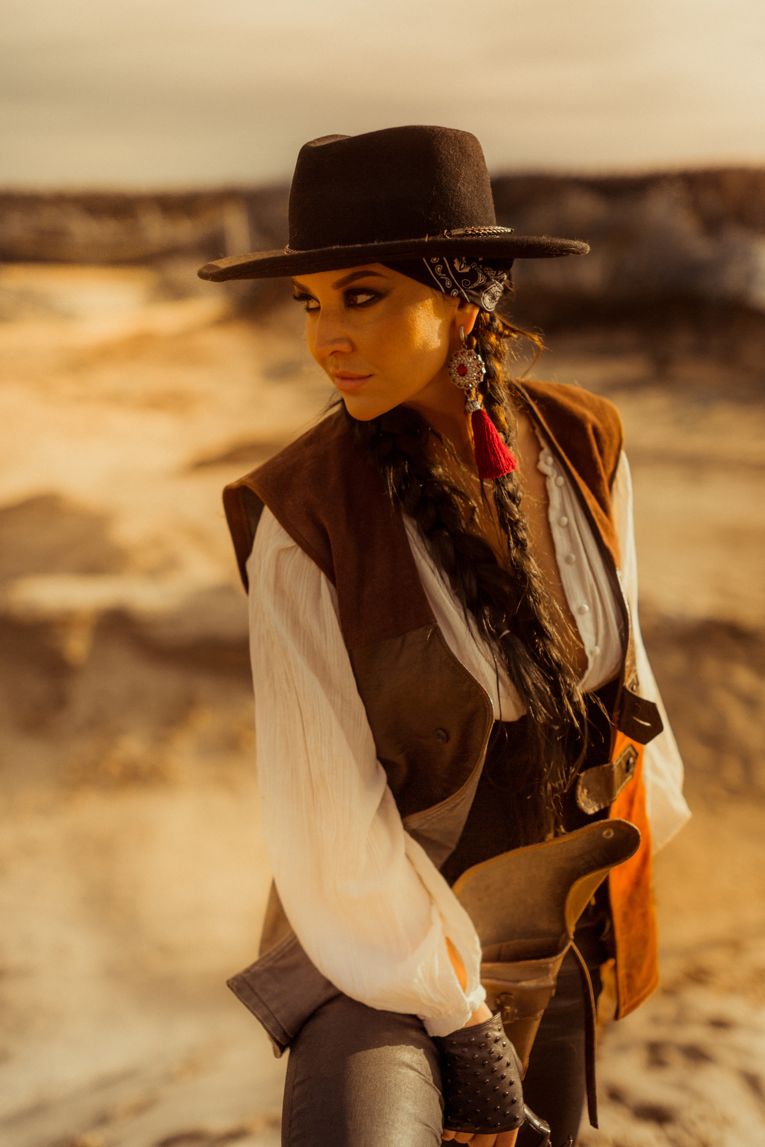 Девушка ковбой с револьвером вестерн на на бархане в пустыне.