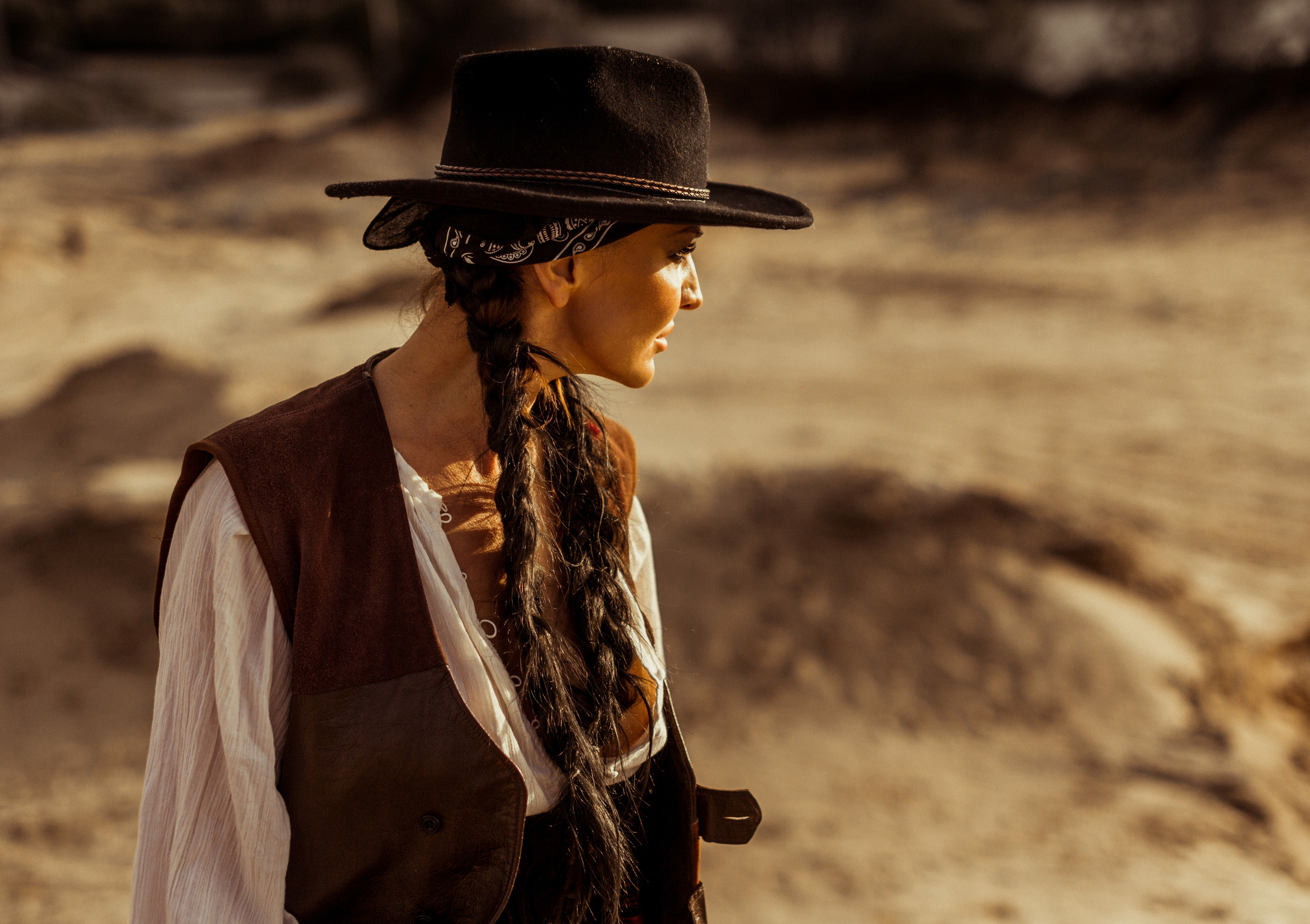 Девушка ковбой с револьвером вестерн на на бархане в пустыне.