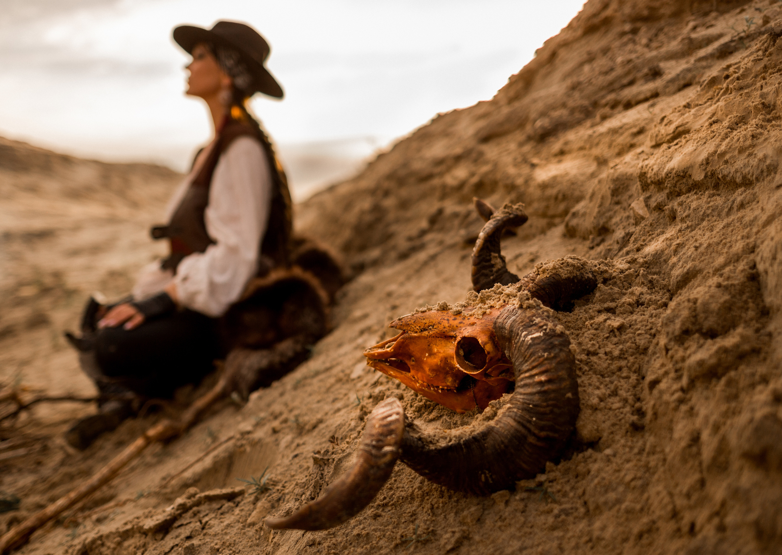 Девушка ковбой вестерн на песчаном карьере в пустыне. Мистический амулет рога барана на переднем плане