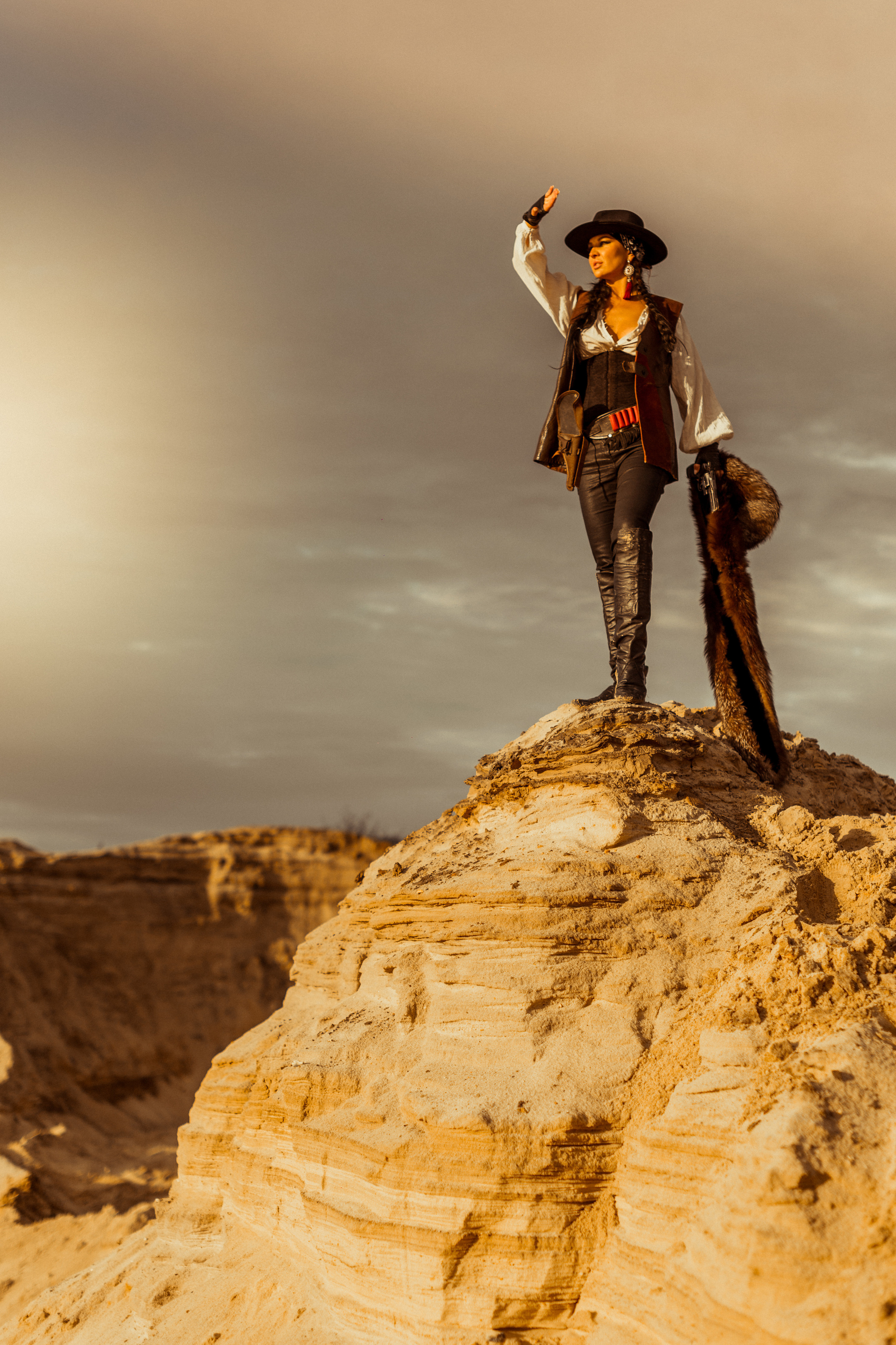 Девушка ковбой с револьвером вестерн на на бархане в пустыне.