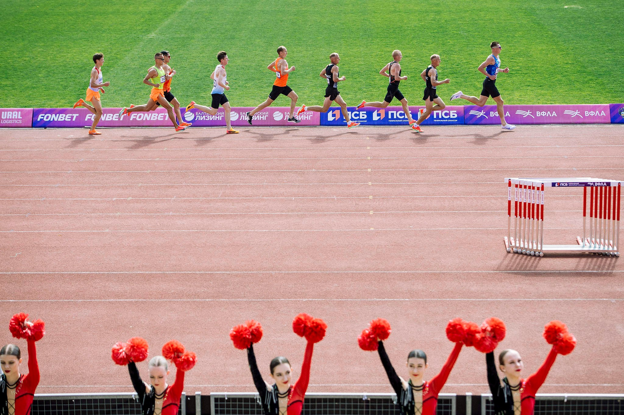 Лидеры забега на 5000 метров пробегают мимо чирлидерс