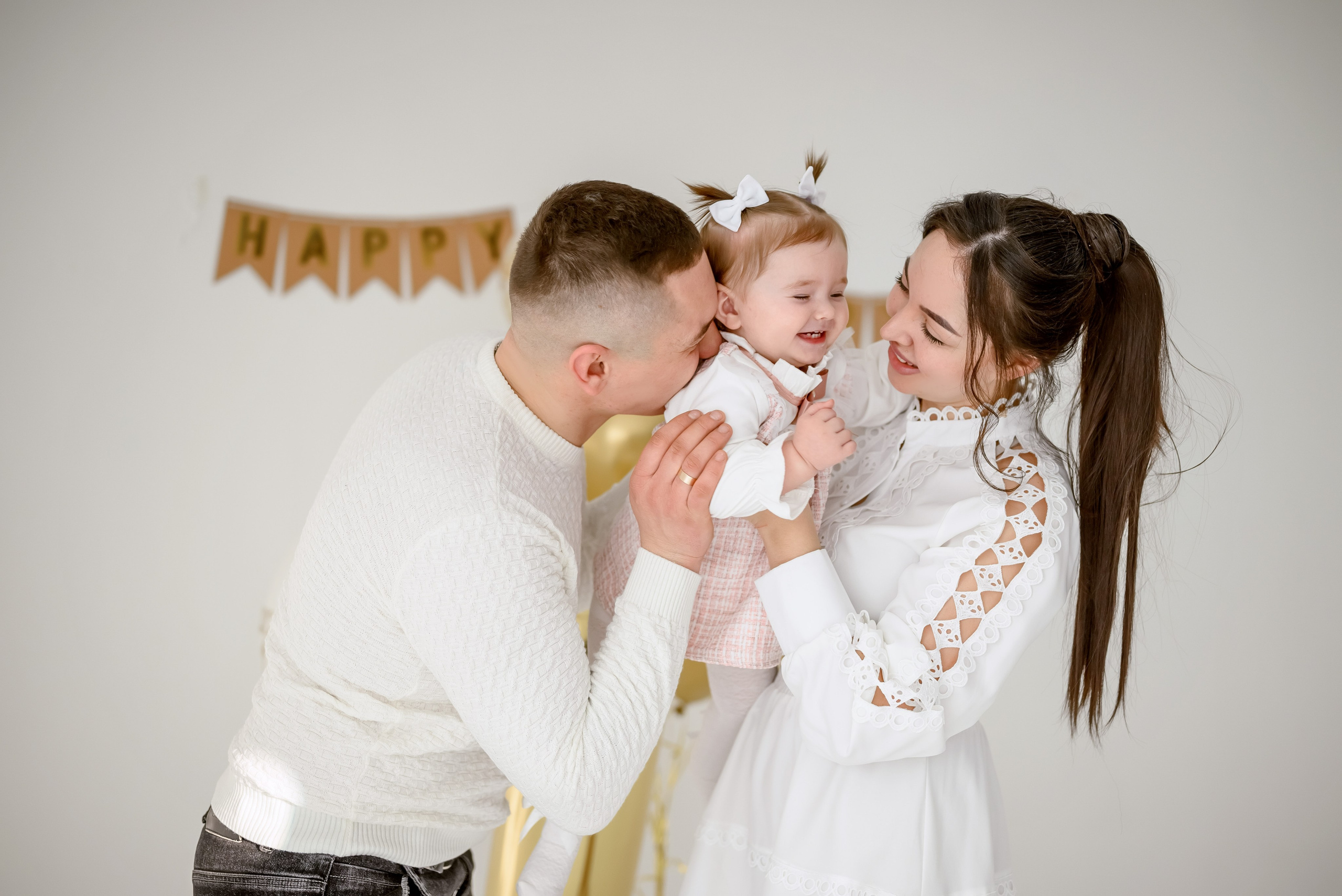 Мама и папа поздравляют свою годовалую дочь на фотосессии