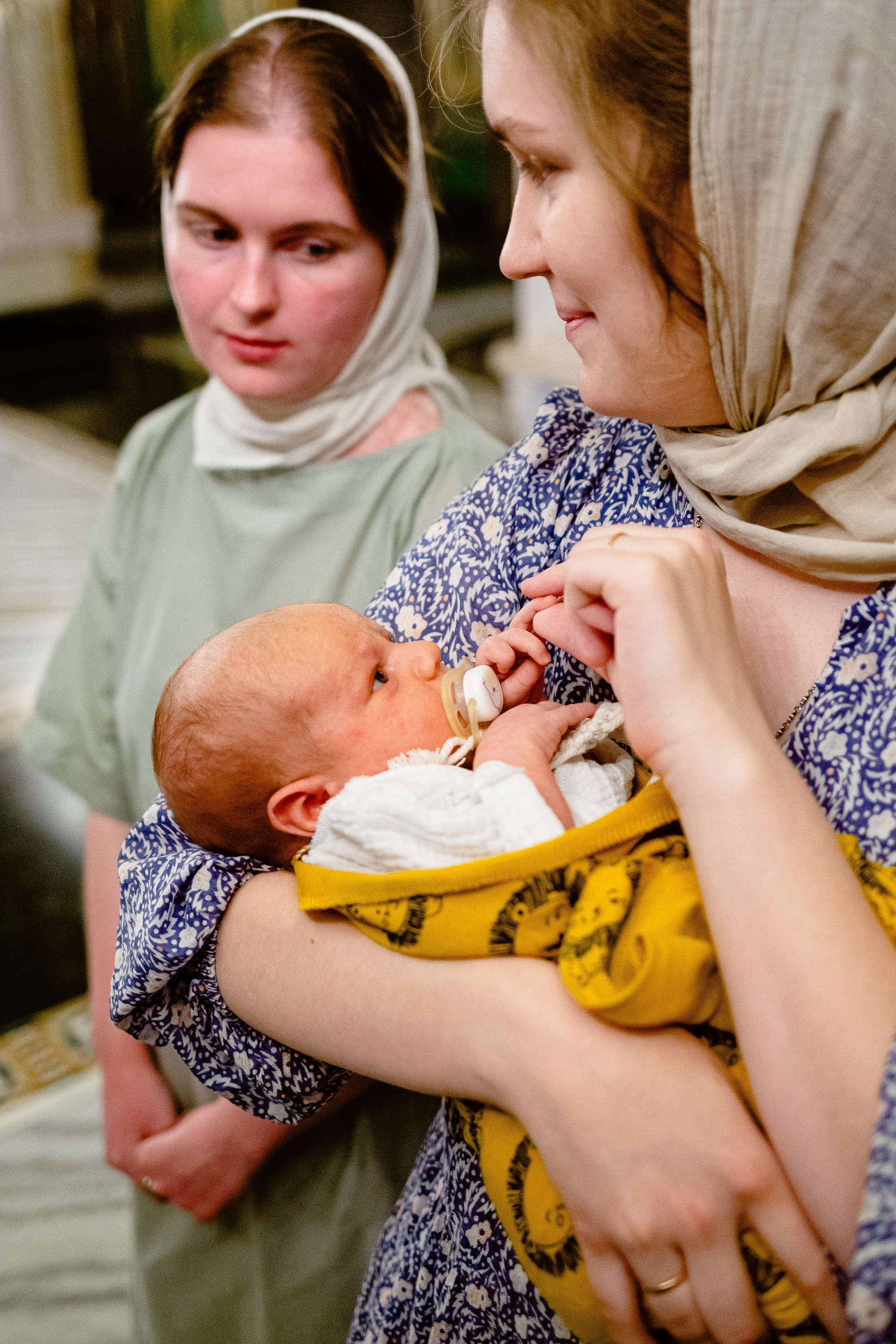 Фотограф на крещение. Мама держит на руках младенца.