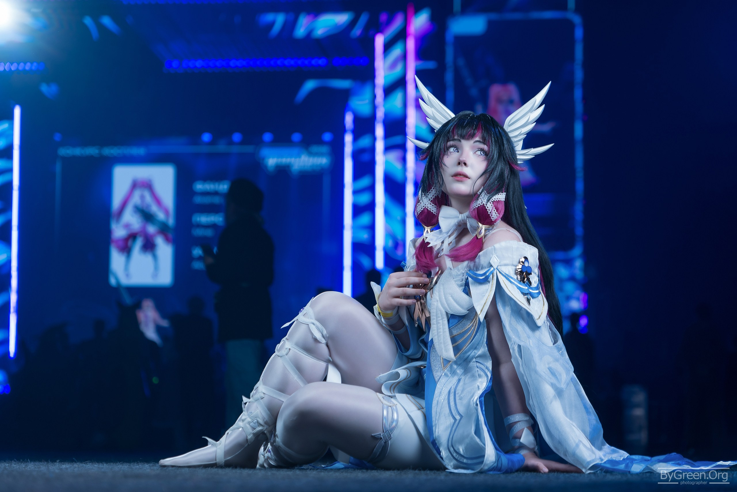 Cosplay of Columbina from Genshin Impact — sitting on stage, wing hair ornaments, Fandom Fest 2026, Moscow