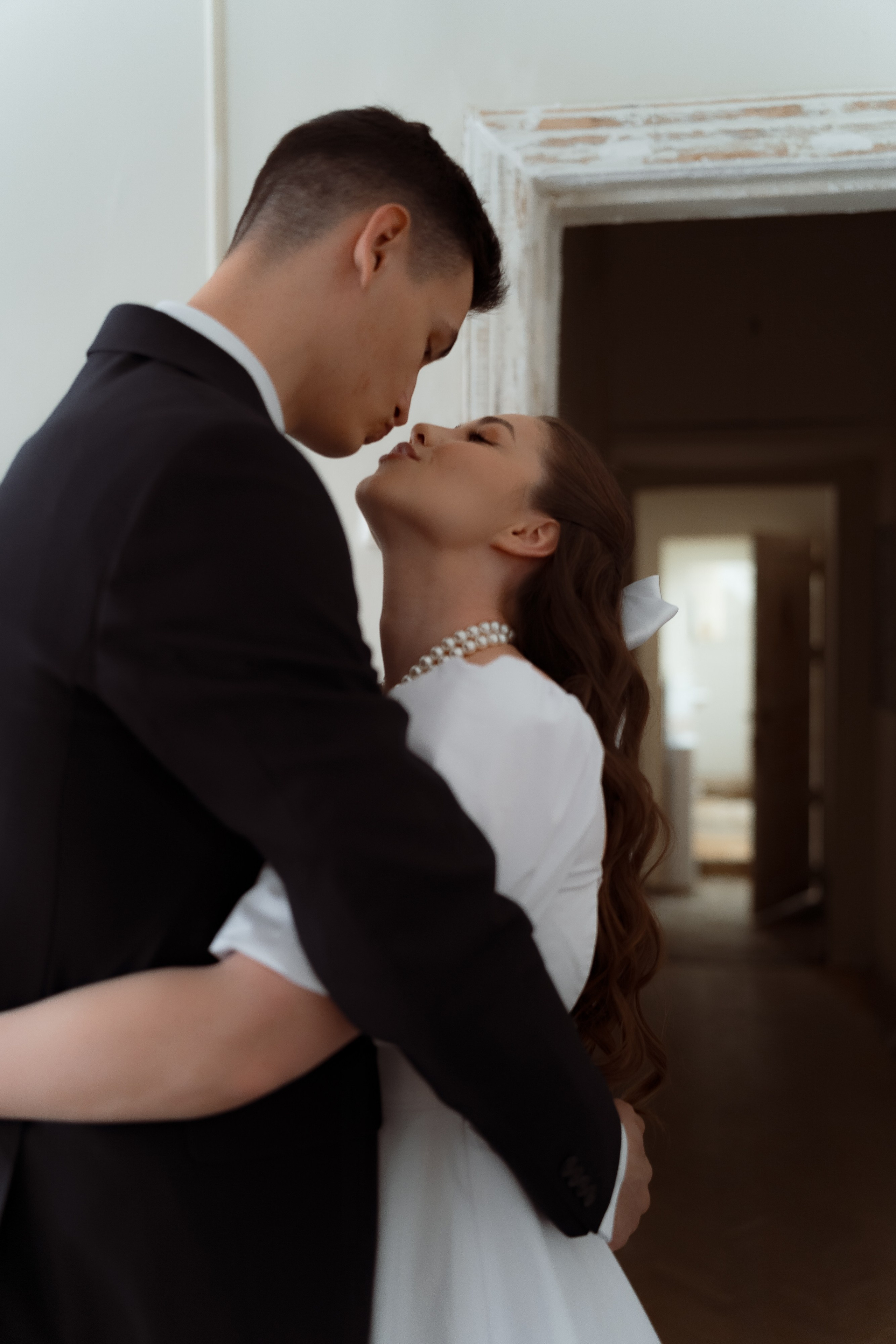 Нежный момент объятий жениха и невесты дома перед церемонией