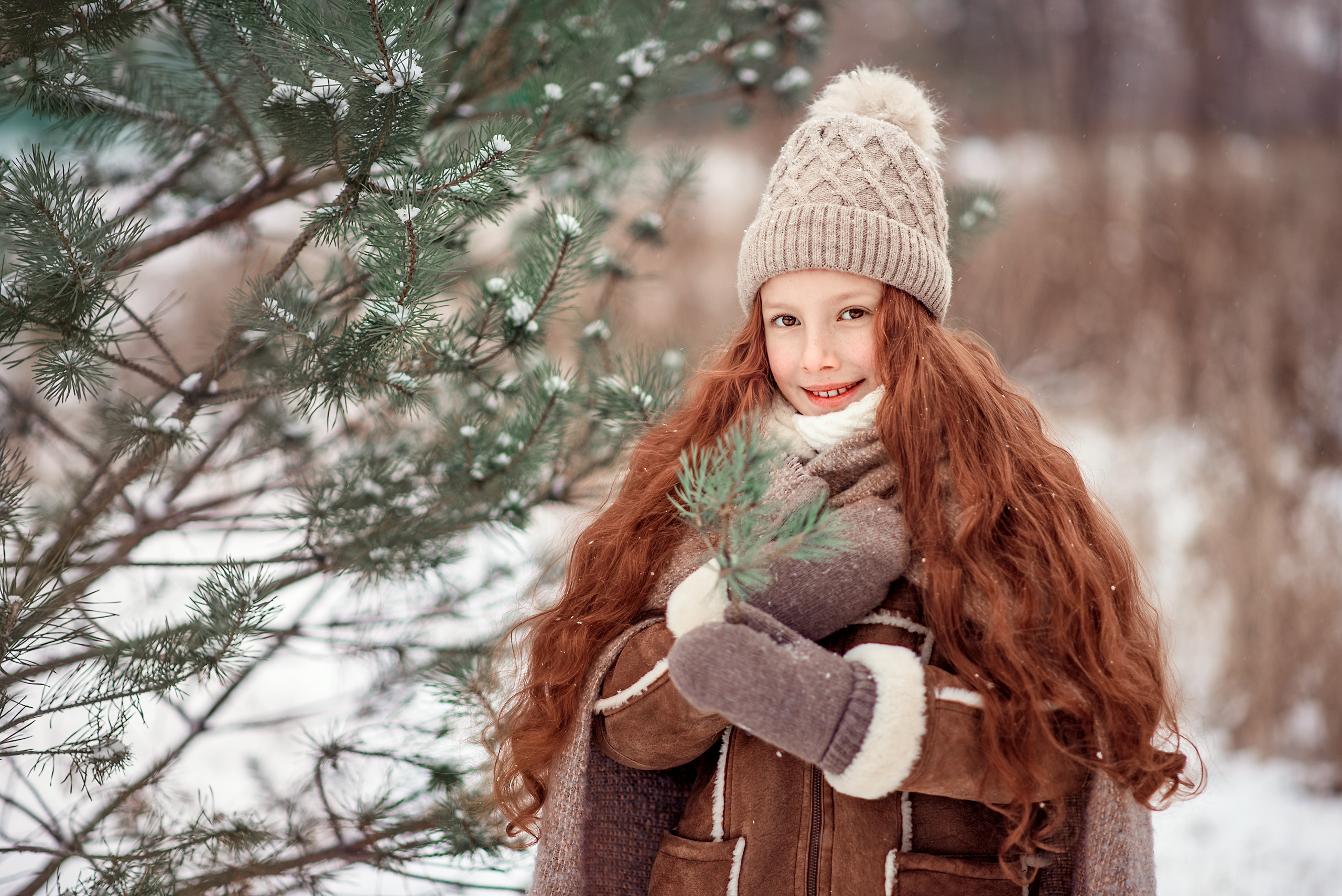 Портрет девочки в зимнем сосновом лесу в веточкой в руках.