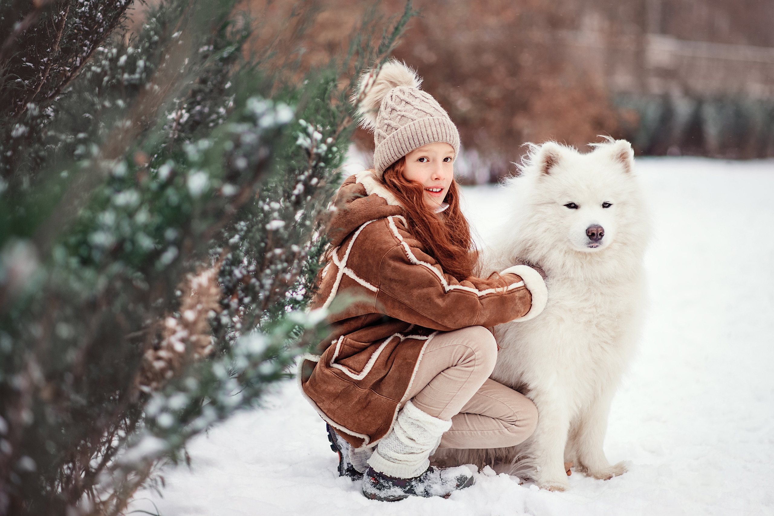 Девочка и самоед смотрят вдаль на фоне зимнего пейзажа.