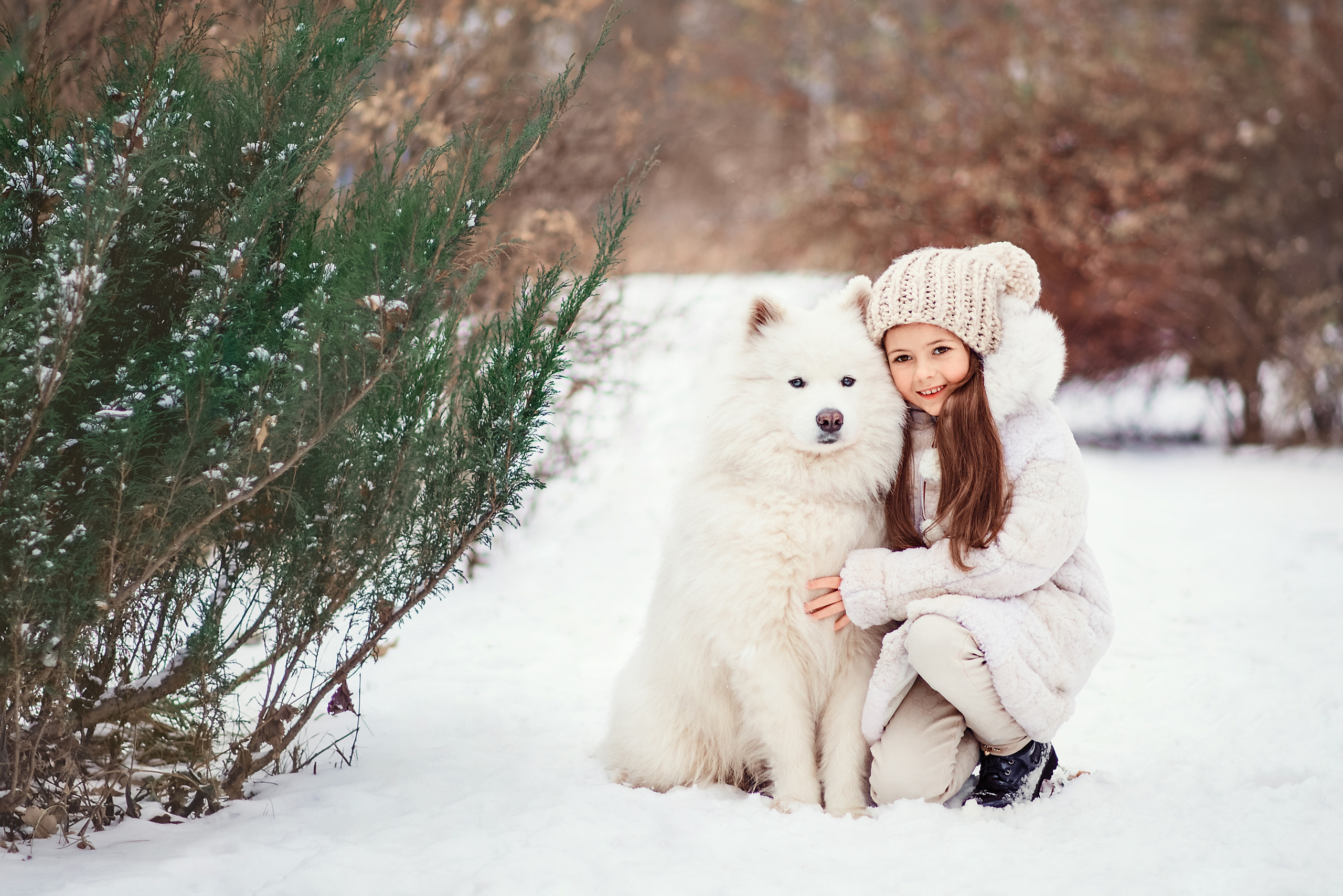 Девочка обнимает самоеда во время зимней фотопрогулки.