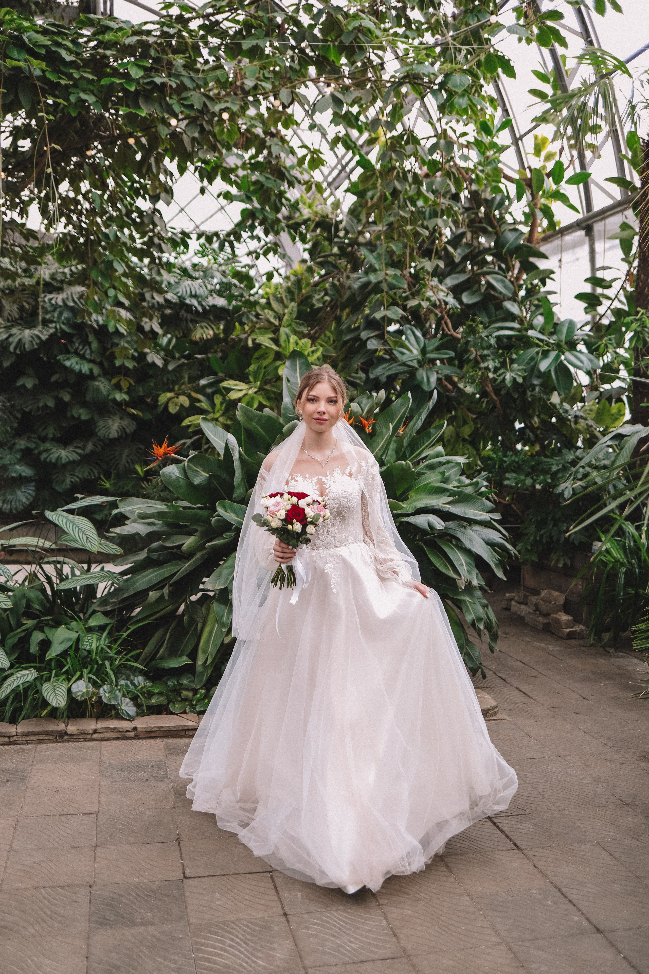 Невеста в платье с букетом среди зелени, полный рост