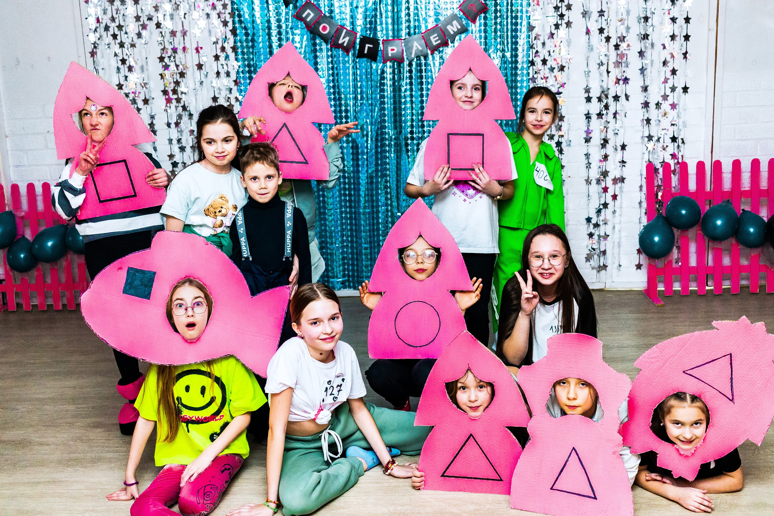 Дети позируют в картонном шаблоне "солдата" розового цвета в конце вечеринки, посвященной сериалу "Игра в кальмара"