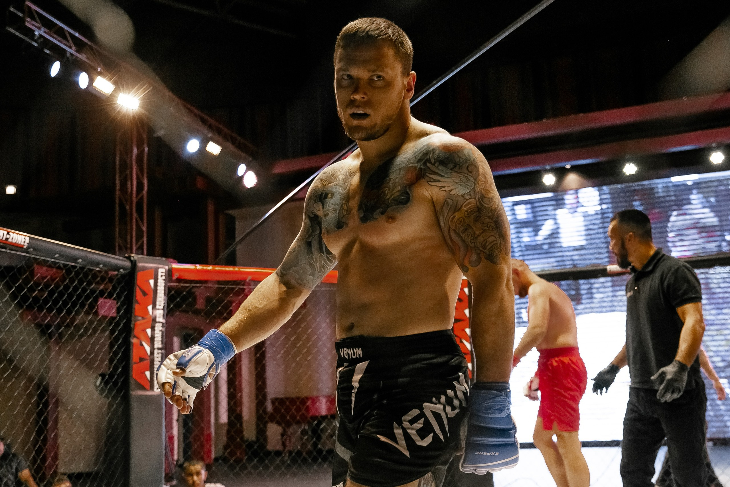 Брутальный боец с татуировкой в октагоне MMA репортажная фотография