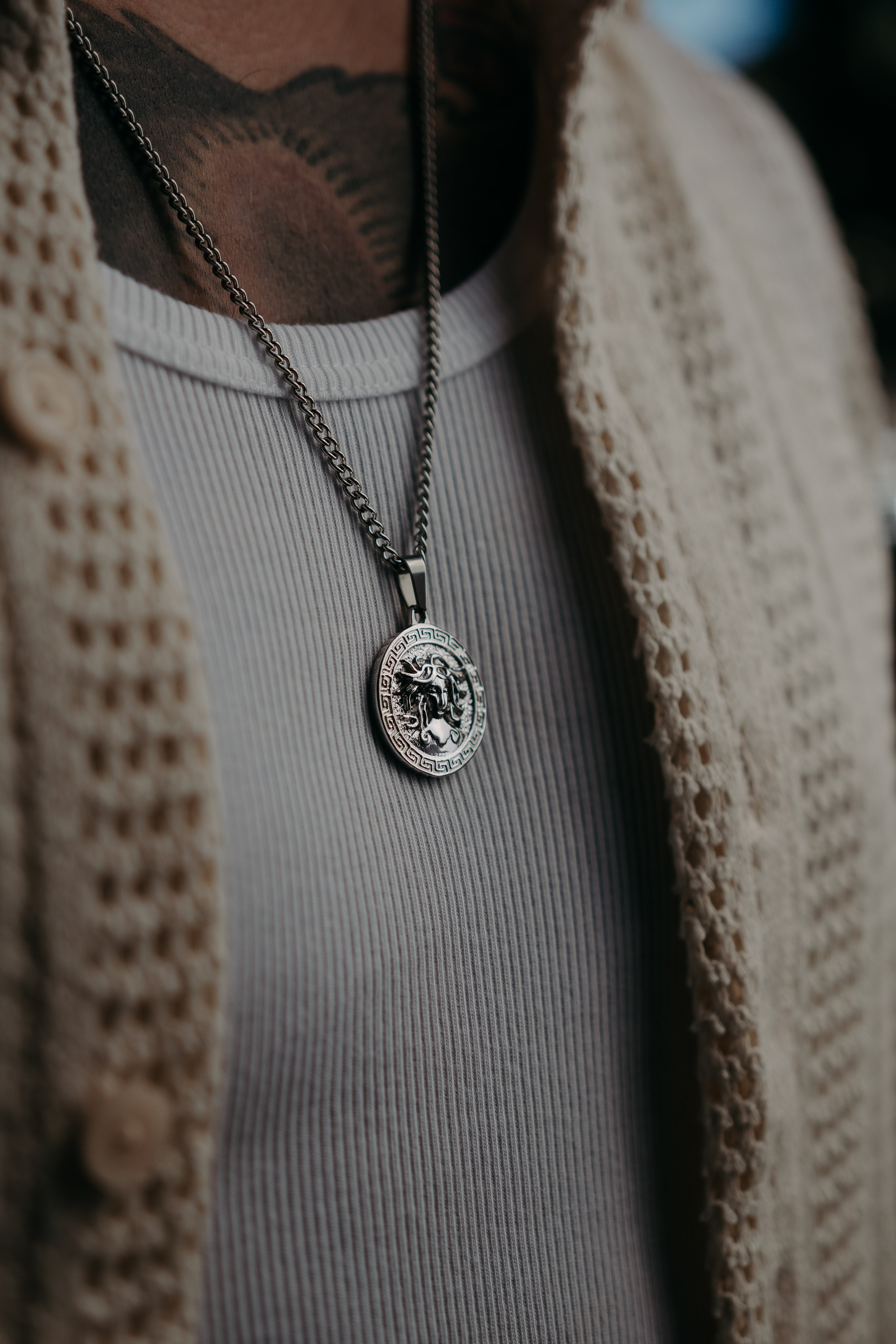Layered silver pendant necklaces styled over a knitted sweater, representing casual and sophisticated fashion.