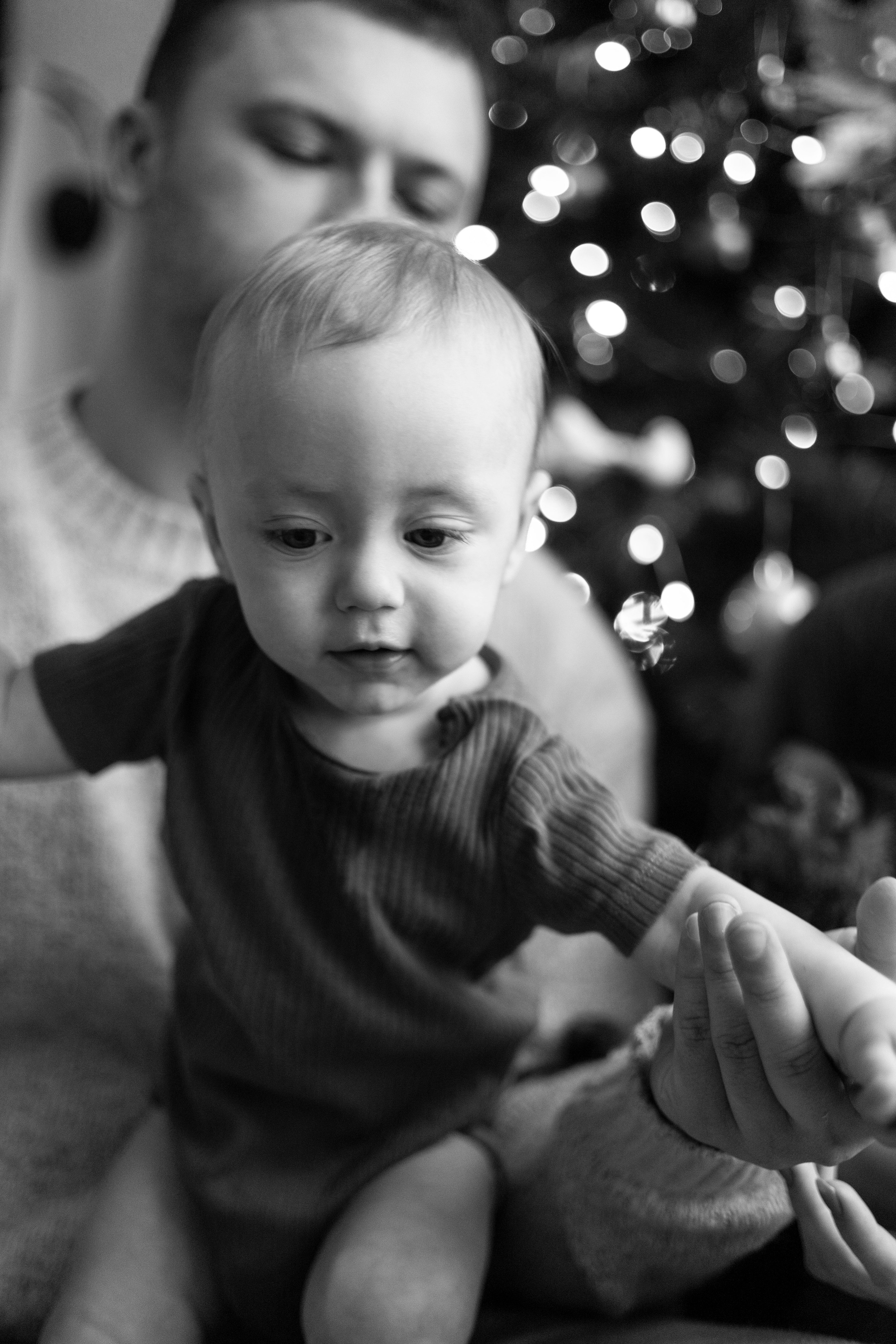 Папа держит сына на коленях у елки