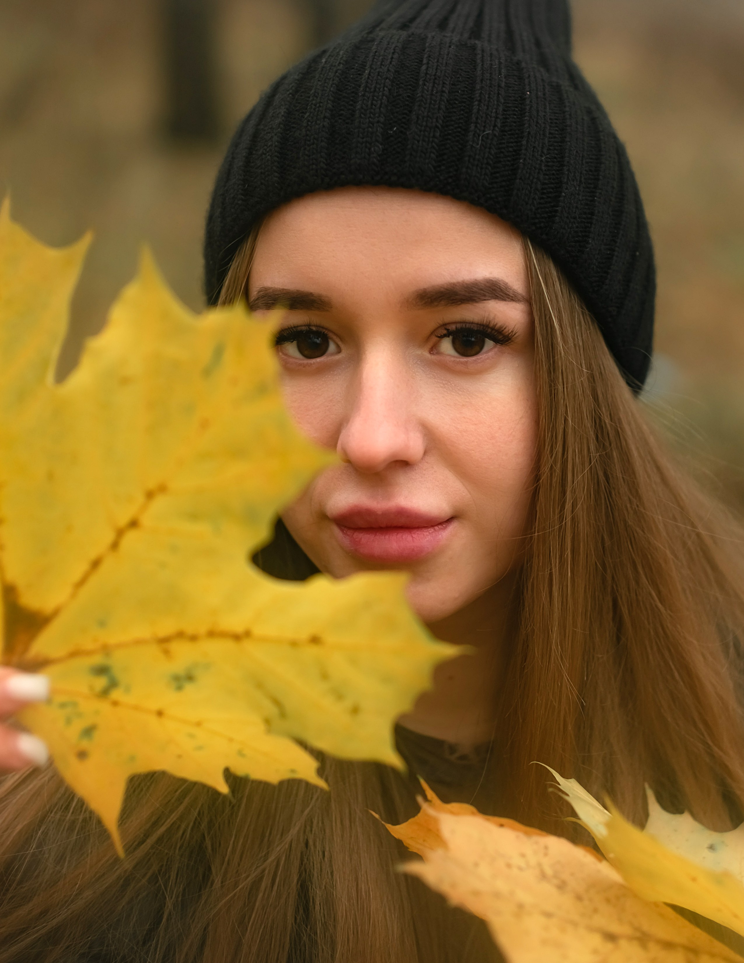 На фото портрет девушки осенним листочком.
