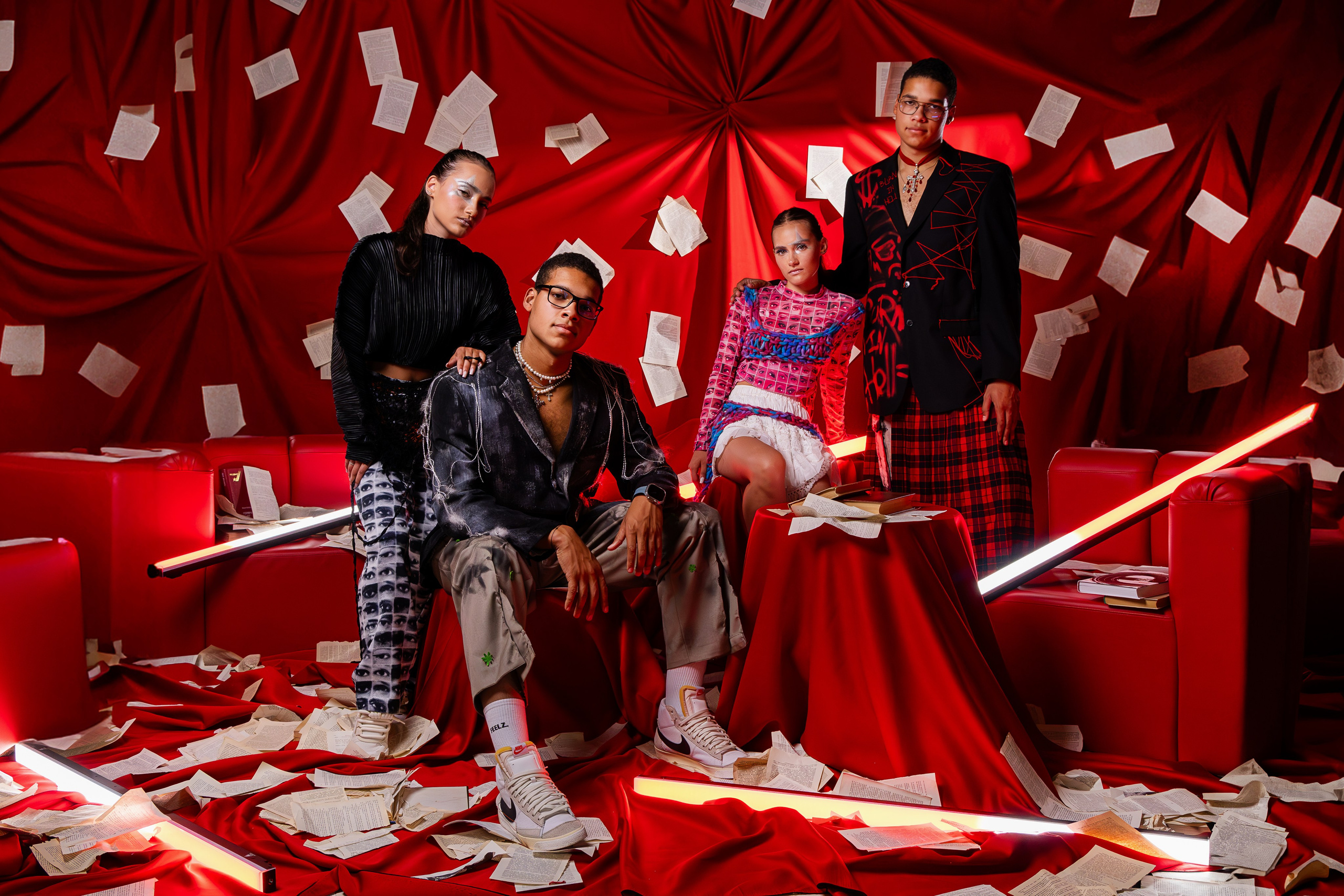 Фотозона, созданная нашей командой в рамках ФотоВидеоФестиваля: яркое красное пространство с оригинальной стилизацией. На фоне из красных тканей и разбросанных листов бумаги позируют четыре модели в современных образах. Стилизованные костюмы и акценты на яркие детали создают контраст с динамичным фоном