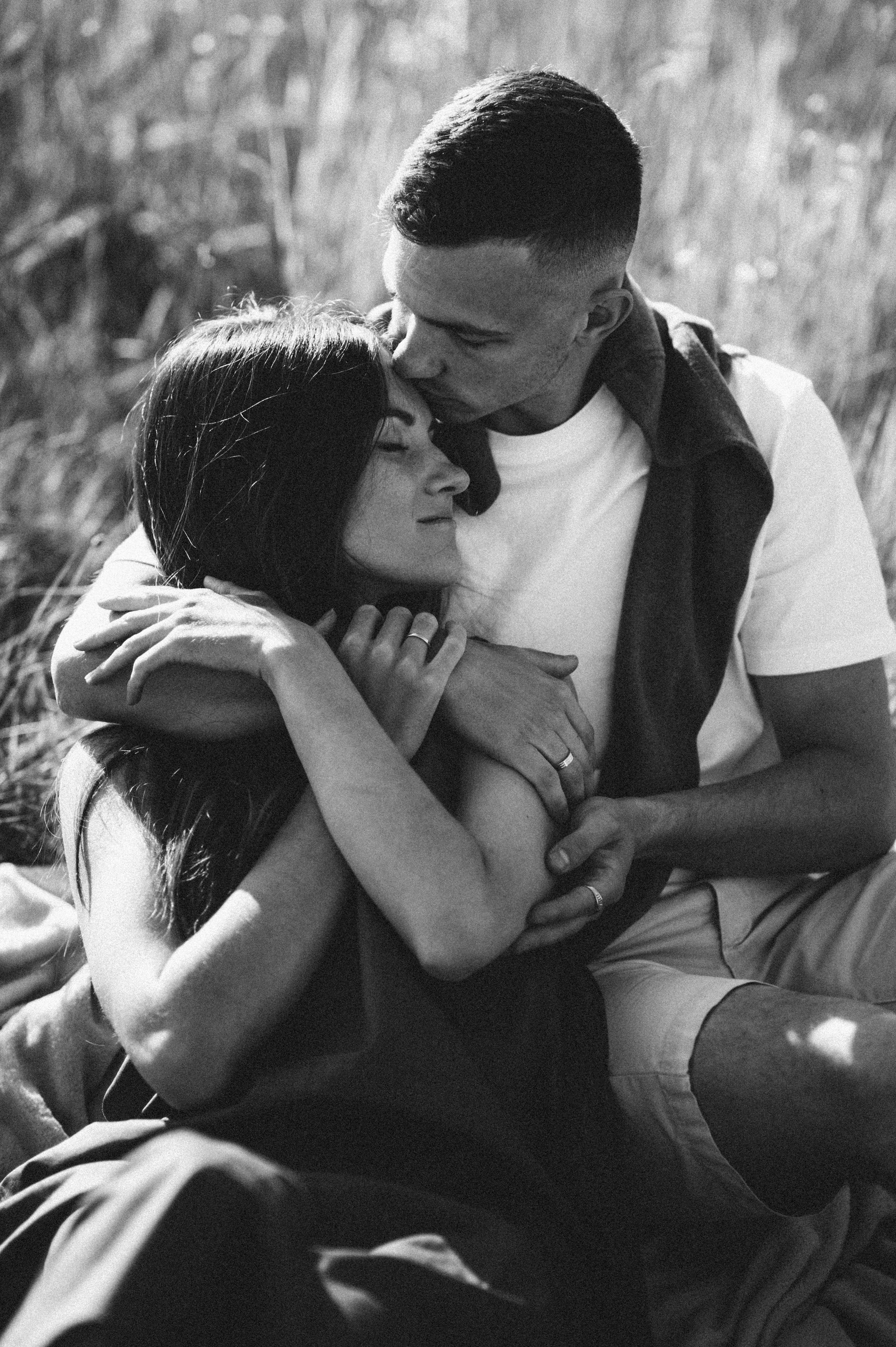 Черно-белая фотография парня который обнимает свою девушку и целует ее в лоб