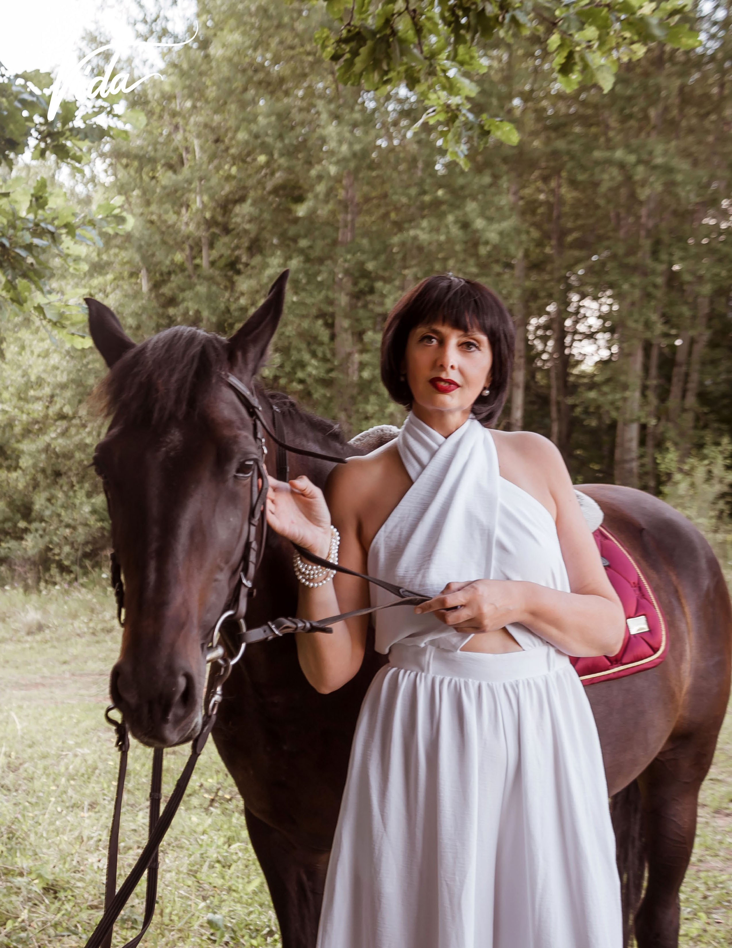 На фото отрывной лист журнала и девушка в белом комбинезоне с лошадкой, держит за уздцы