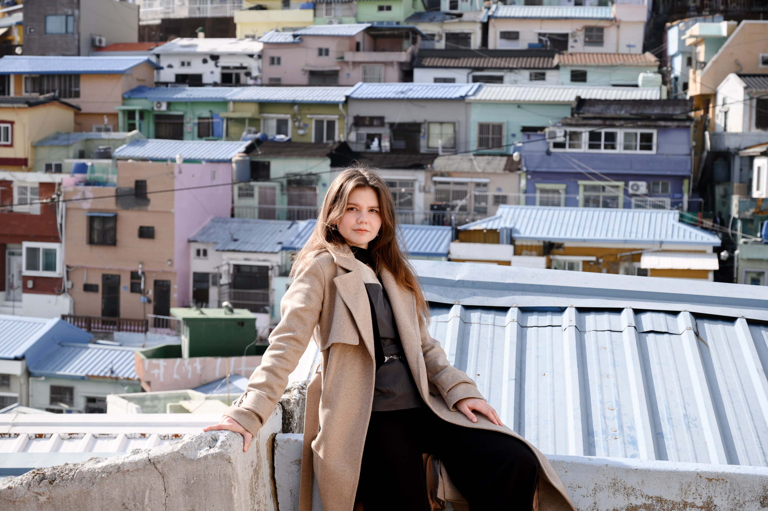Woman in a beige coat against the colorful houses of Gamcheon Culture Village, Busan · 釜山 旅行フォト