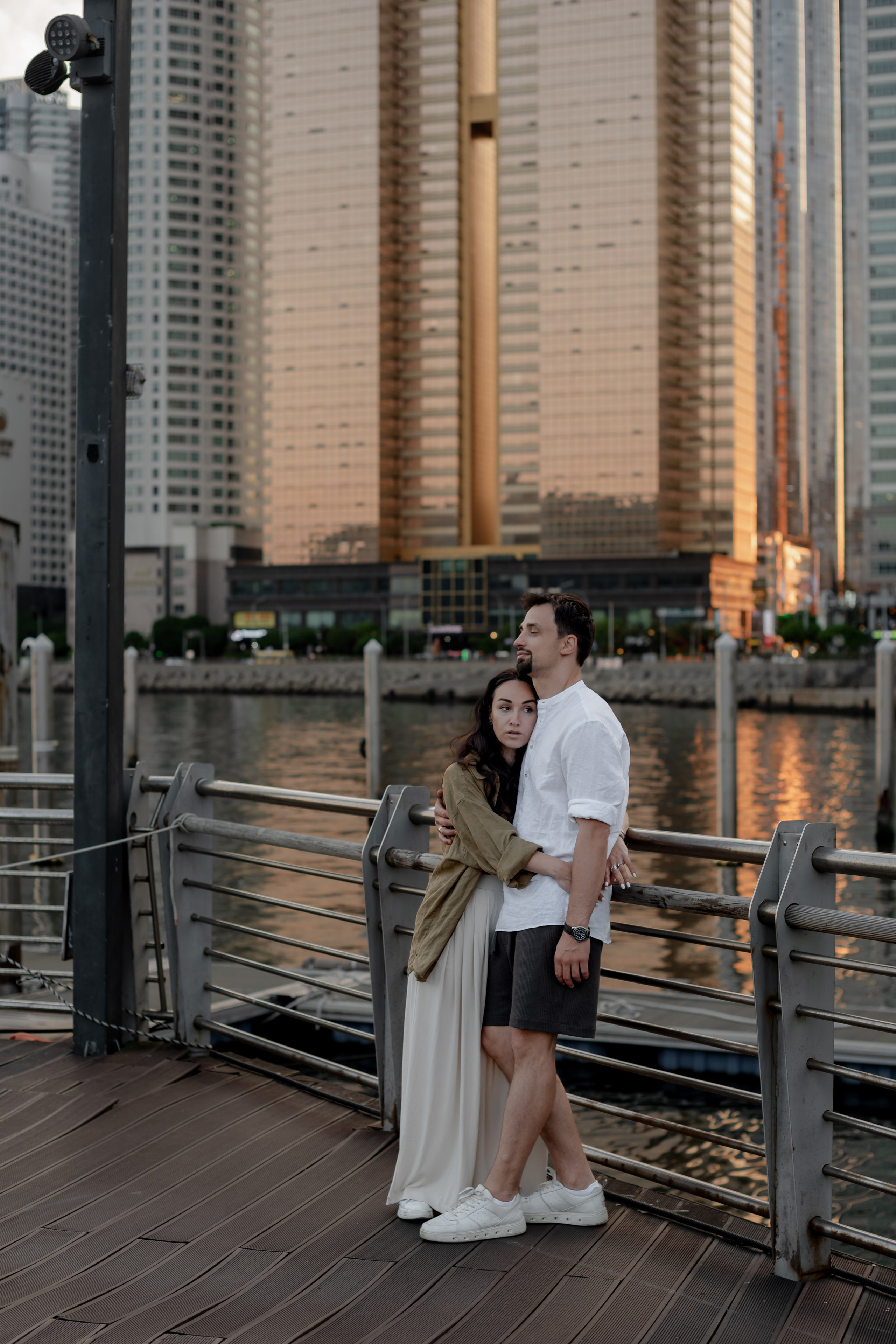 Couple on a wooden boardwalk among the Haeundae skyscrapers, Busan — travel photoshoot · 부산 여행 스냅