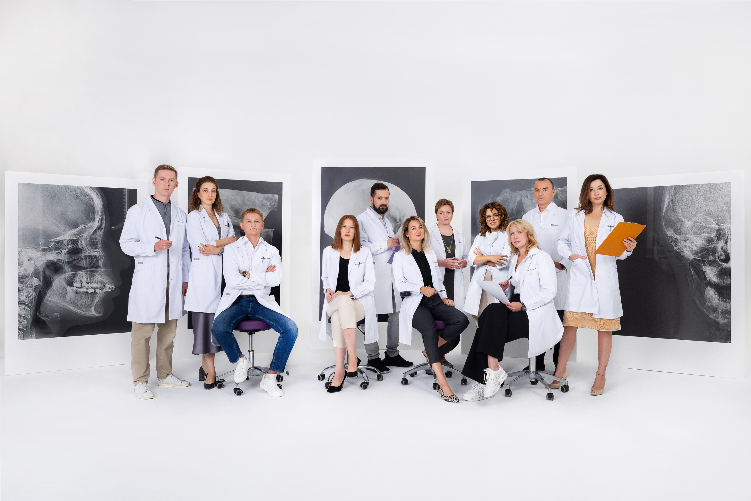 Съёмка для Федеральной сети независимых центров рентгенодиагностики «Пикассо». На фото группа профессионалов в белых халатах, стоящих и сидящих перед рентгеновскими снимками на фоне белой стены. В центре снимка врачи и медицинский персонал. В их руках различные инструменты, такие как папки с документами и медицинское оборудование. Все выражают уверенность и профессионализм