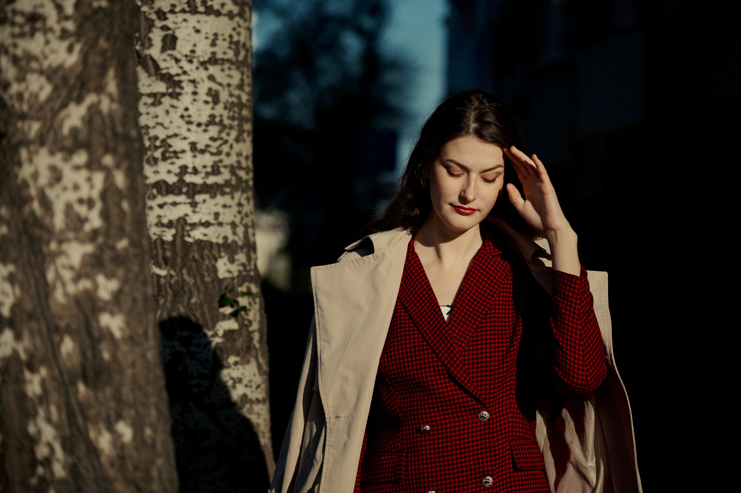 Тёплый портрет в городе: женщина идёт вдоль улицы в пальто, мягкий свет подчеркивает образ.