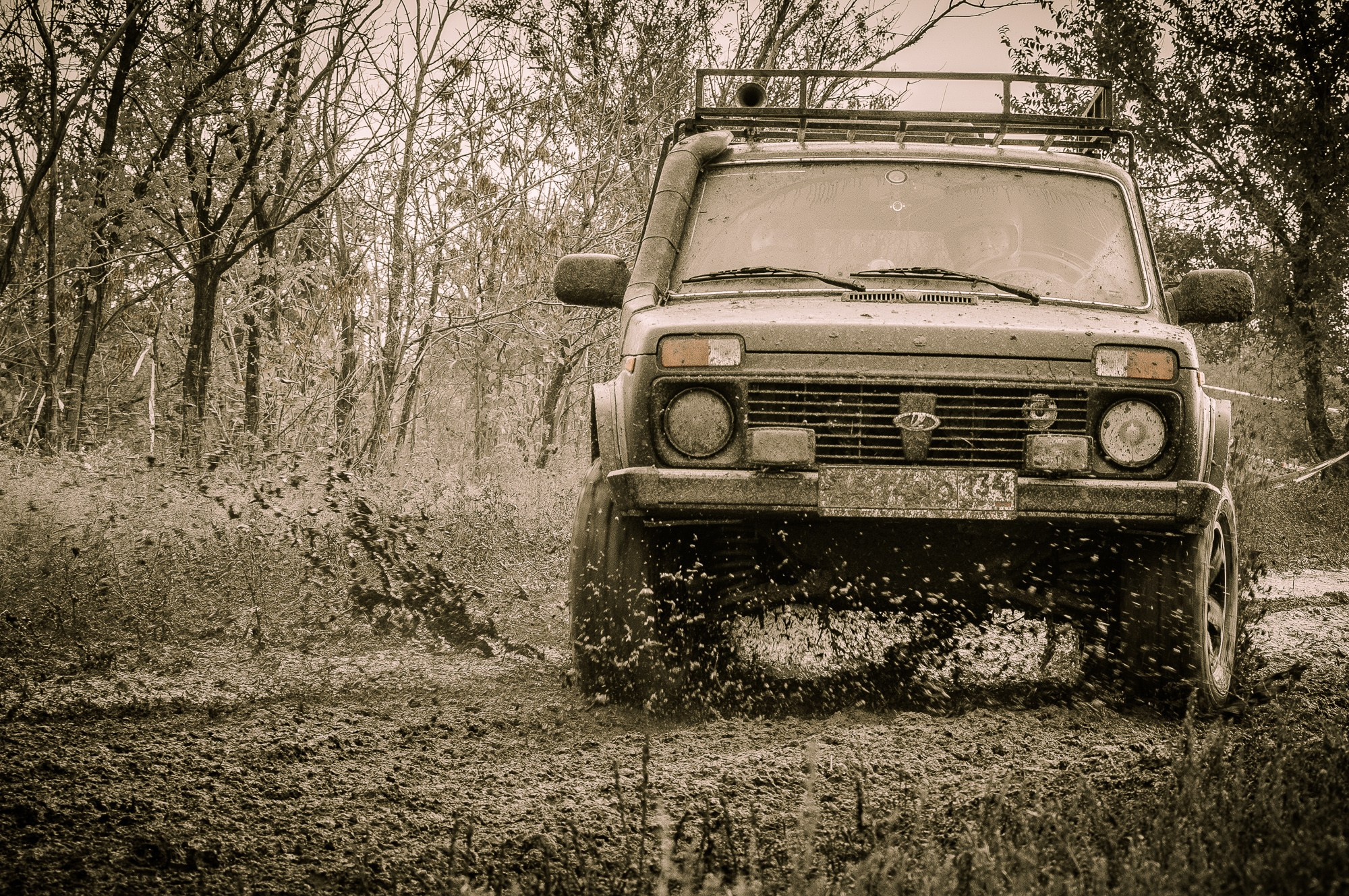 Автомобиль Нива разбрызгивает грязь на бездорожье