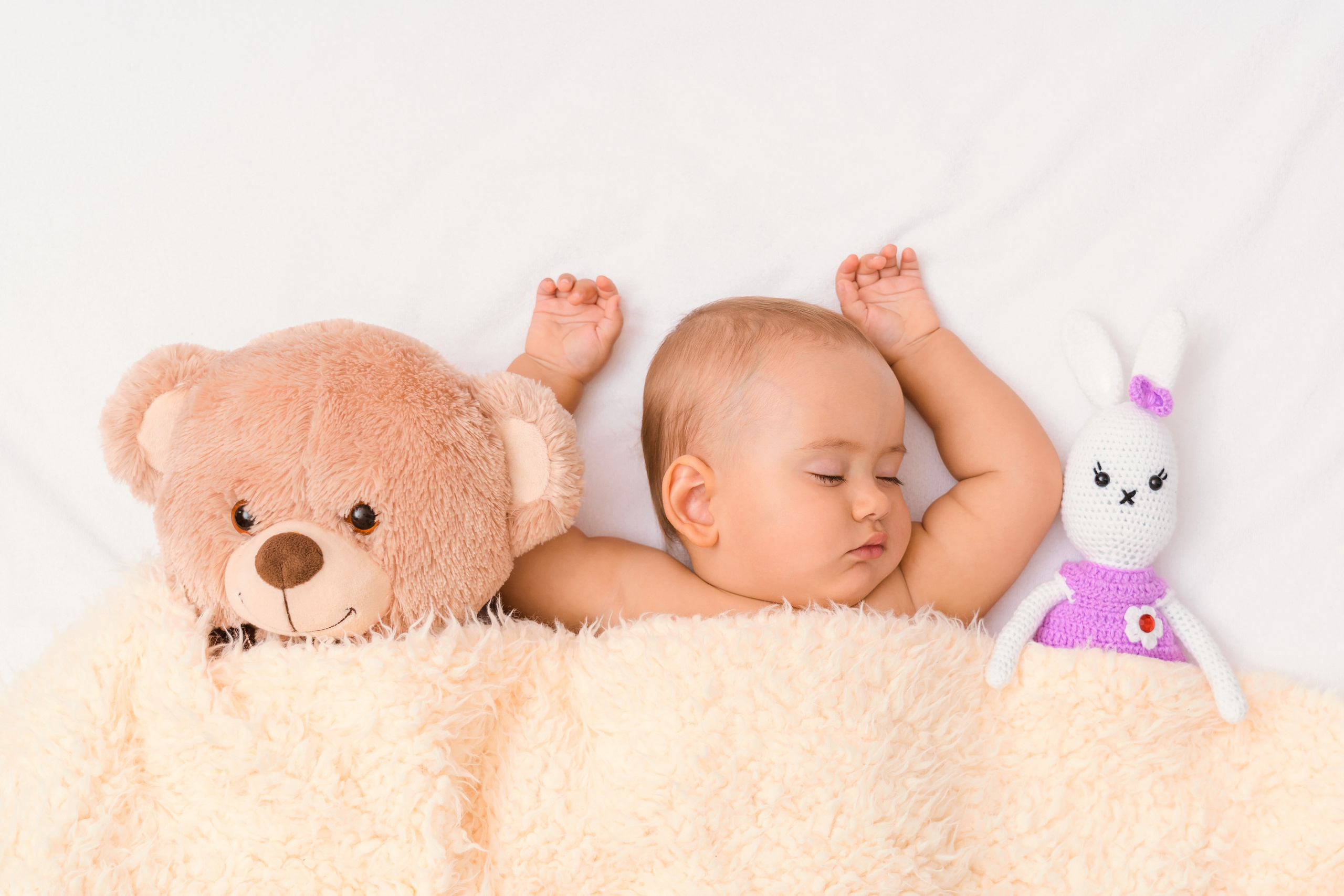 Фотосессия новорожденных детей, ребенок спит рядом с любимыми игрушками