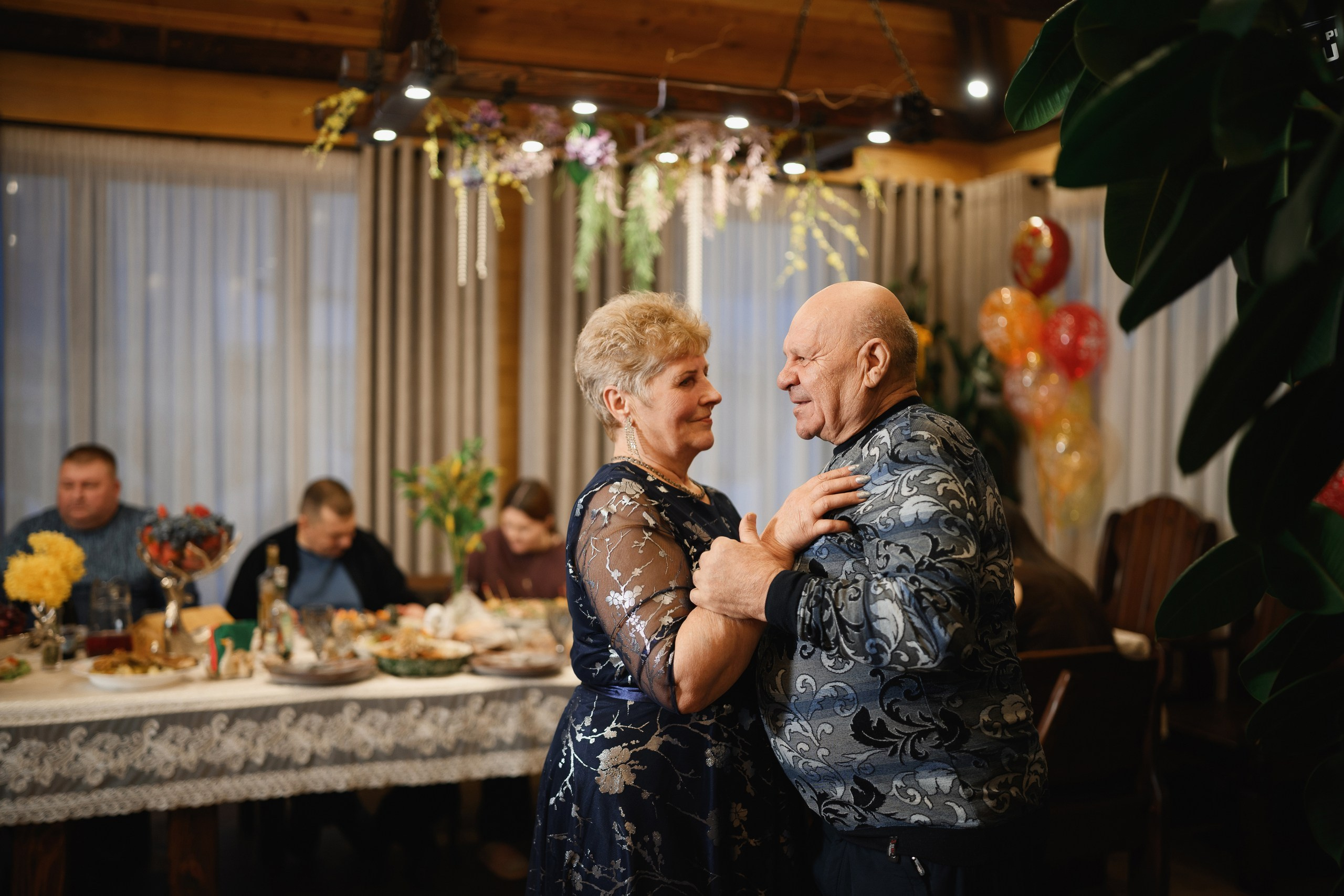 Пожилая пара танцует на семейном празднике за праздничным столом, тёплая атмосфера и живые эмоции, Петропавловск-Камчатский.