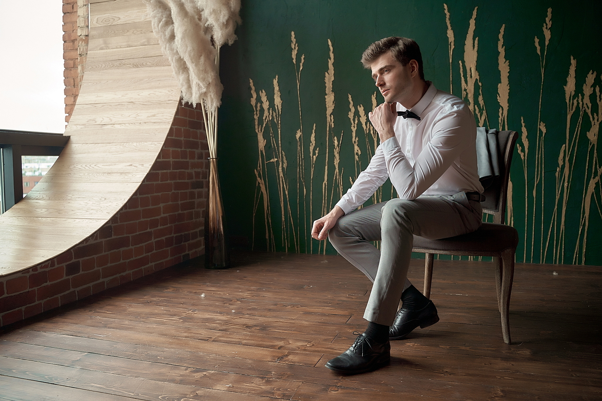 жених красиво сидит на стуле у окна. Утро жениха. Свадебный фотограф Сергей Гаварос. Москва +792566963199