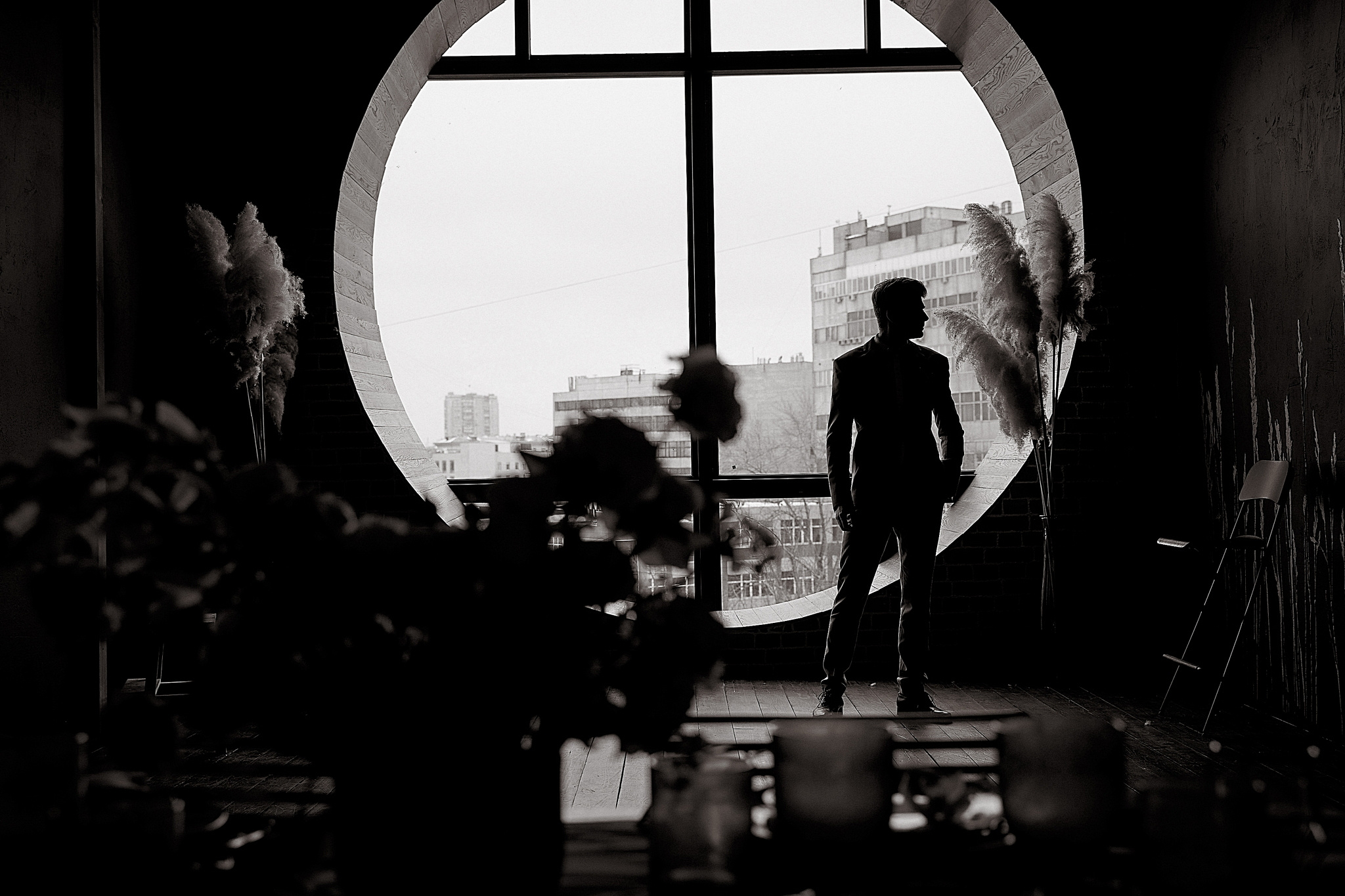 Силует жениха на фоне круглого окна. Утро жениха. Свадебный фотограф Сергей Гаварос. Москва +792566963199