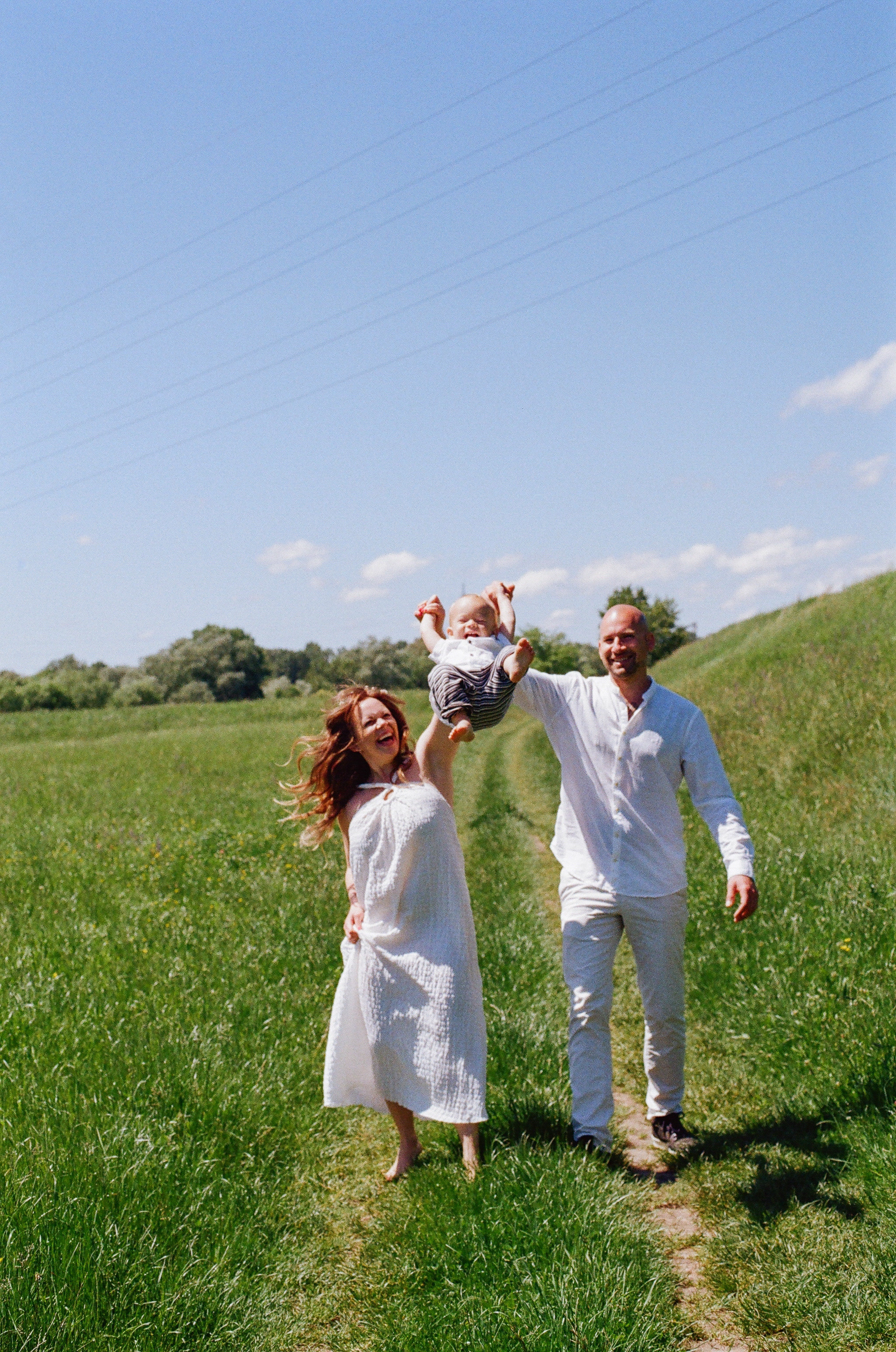dad and mom holding hands and lifting the baby in the air