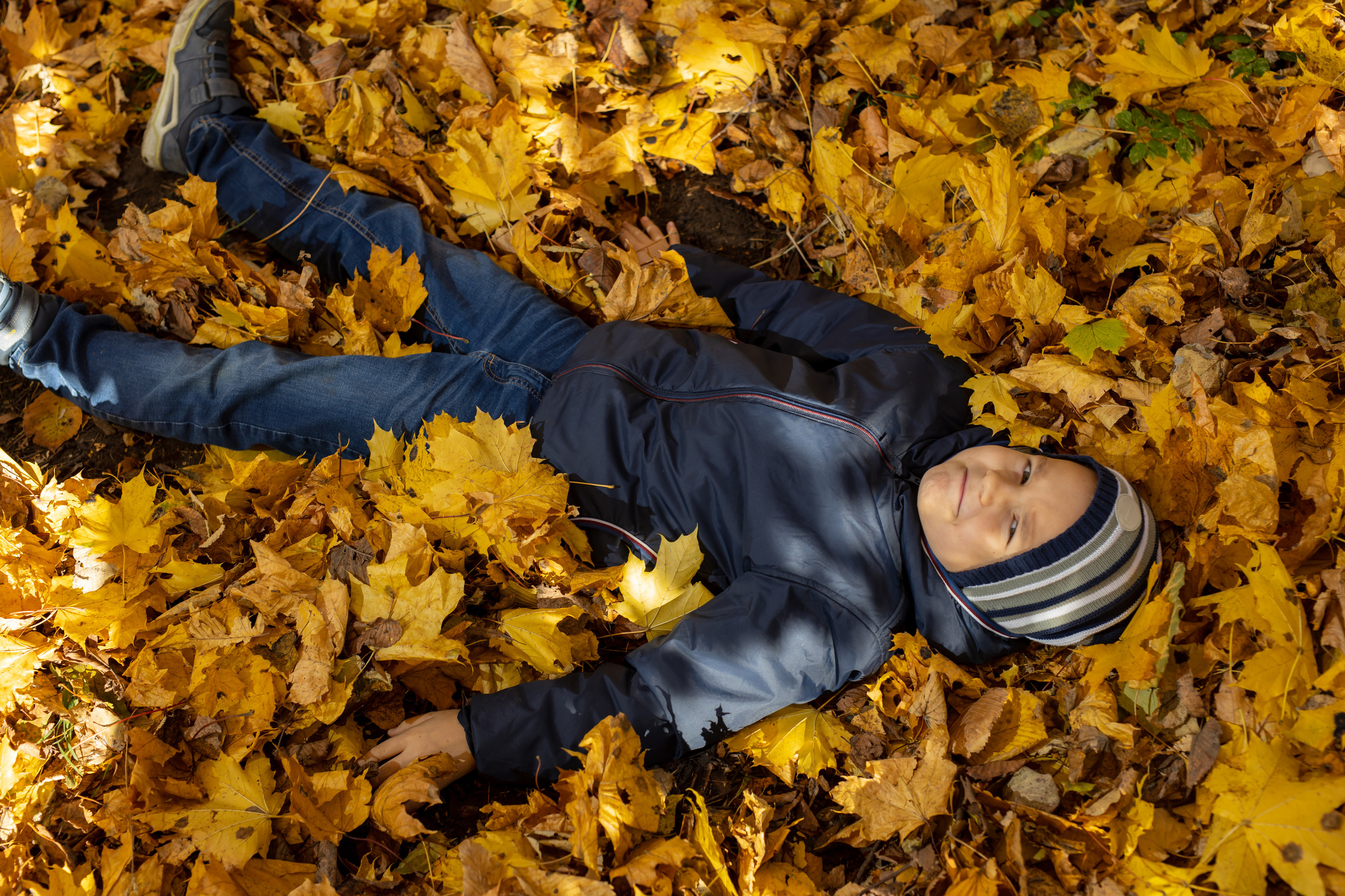 Счастливы мальчик во время съемки лежит в осенних листьях
